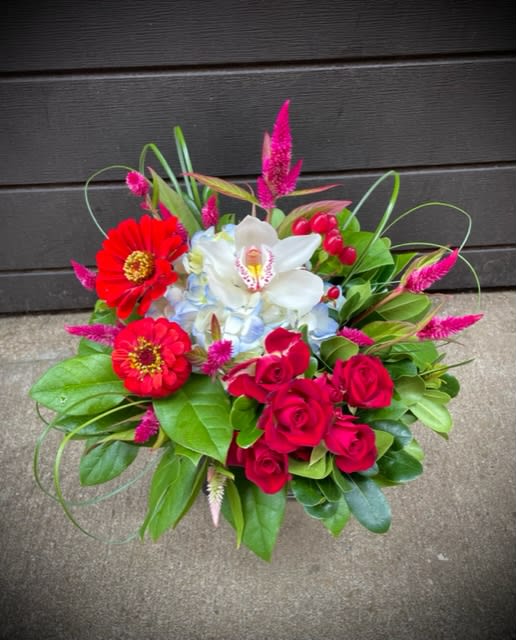 Bouquet of red roses, white orchid, and red zinnias with pink accents