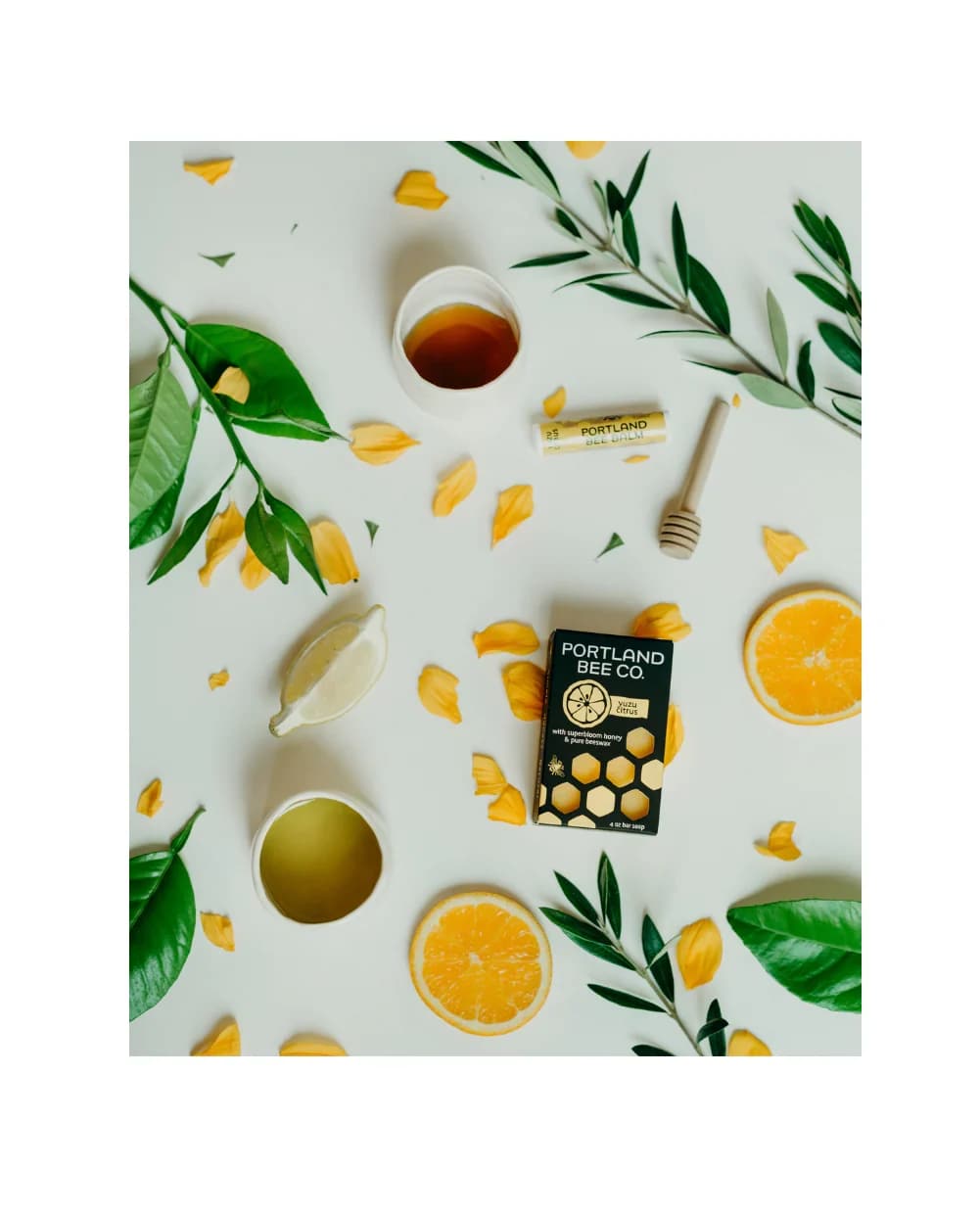 Honey soap bar with citrus slices and green leaves on a white background
