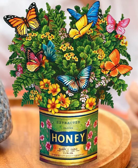Butterfly-themed floral arrangement in a honey can container