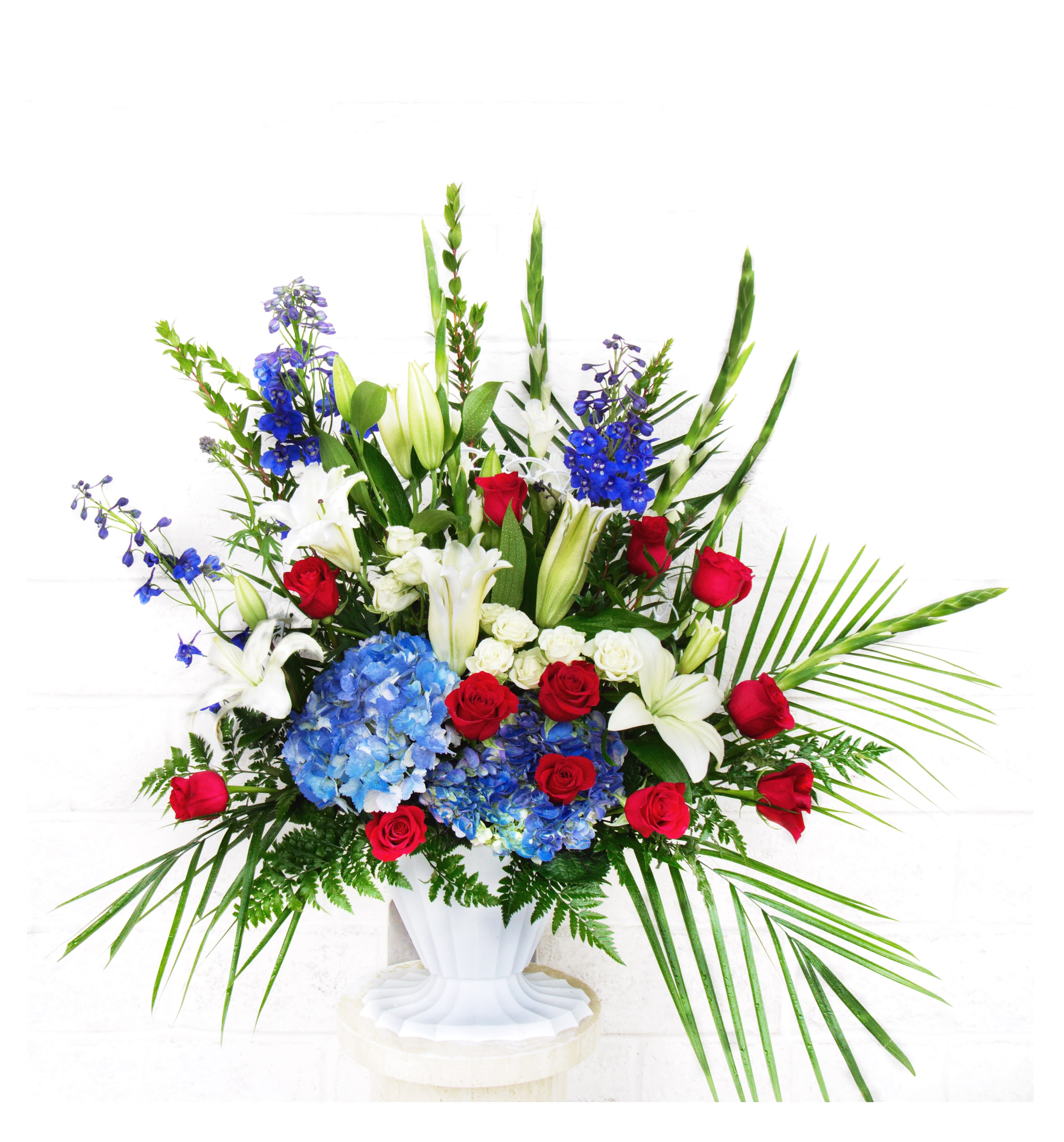 Large arrangement of red roses, white lilies, and blue hydrangeas in a white vase