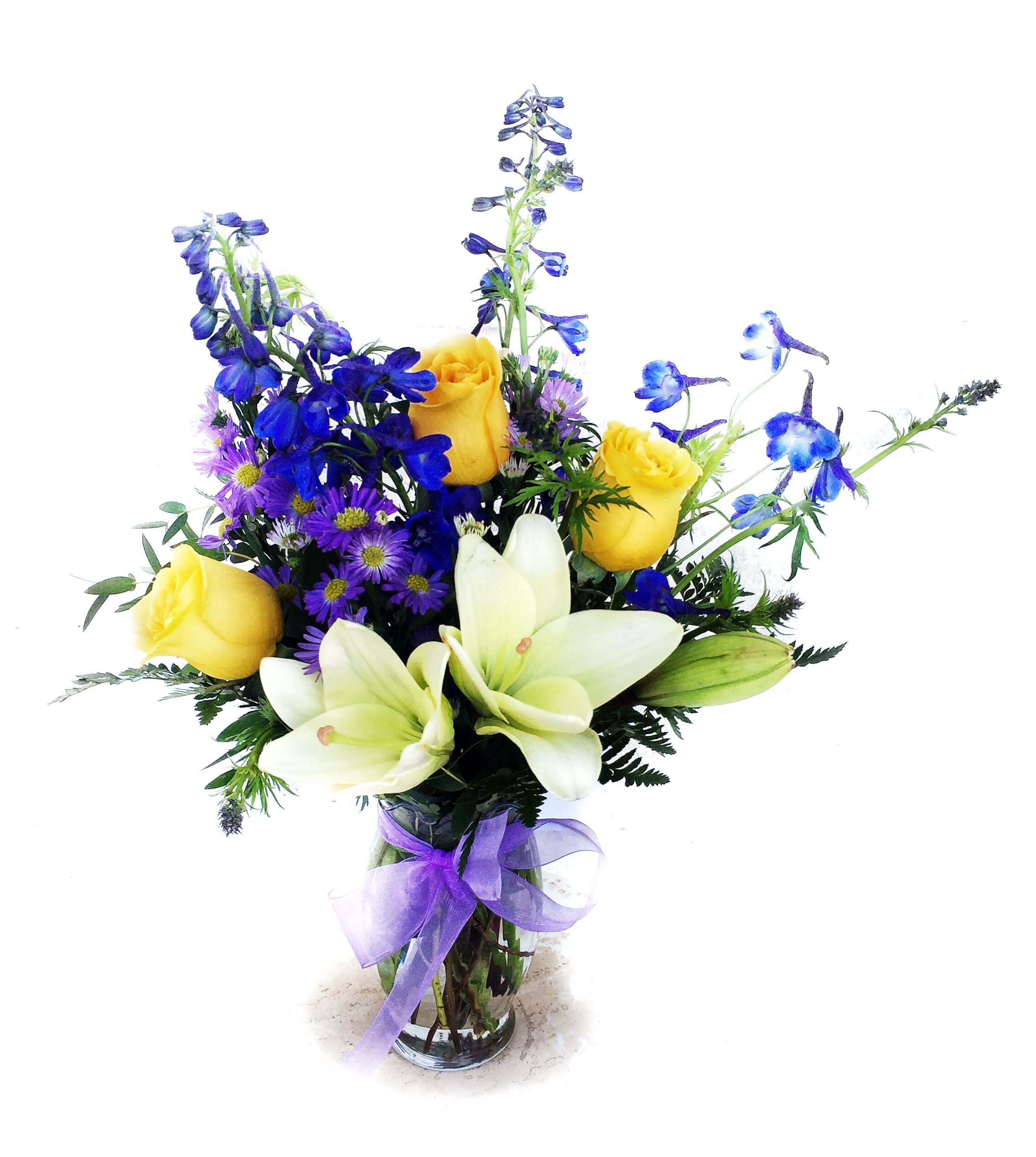 Bouquet of yellow roses, white lilies, and blue flowers in a glass vase