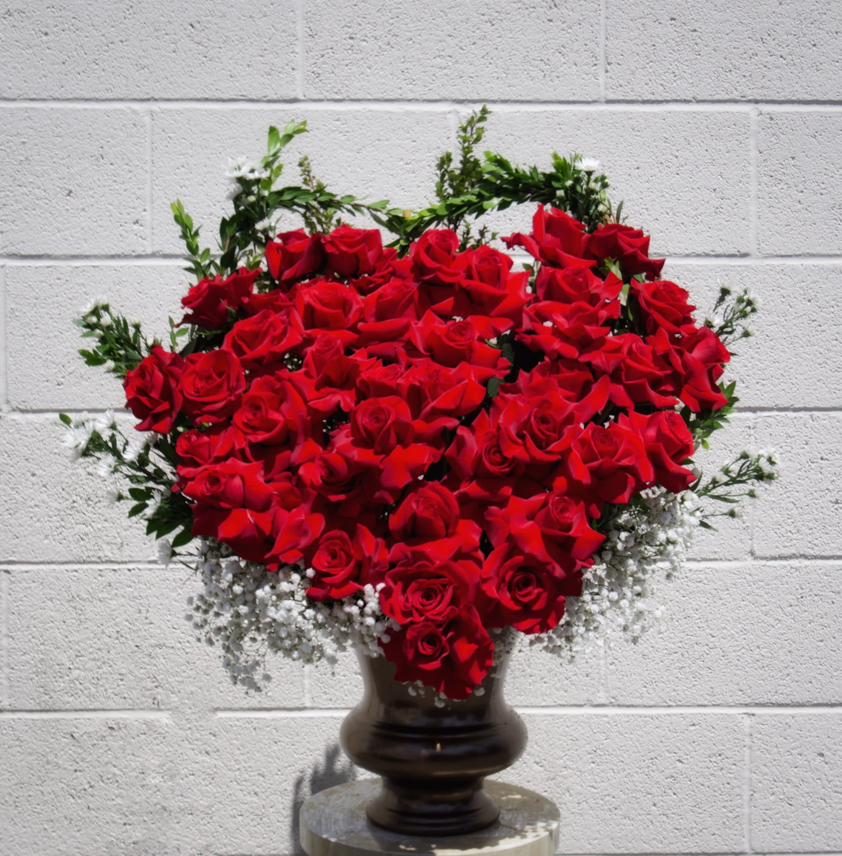 Heart-shaped arrangement of red roses in a dark vase