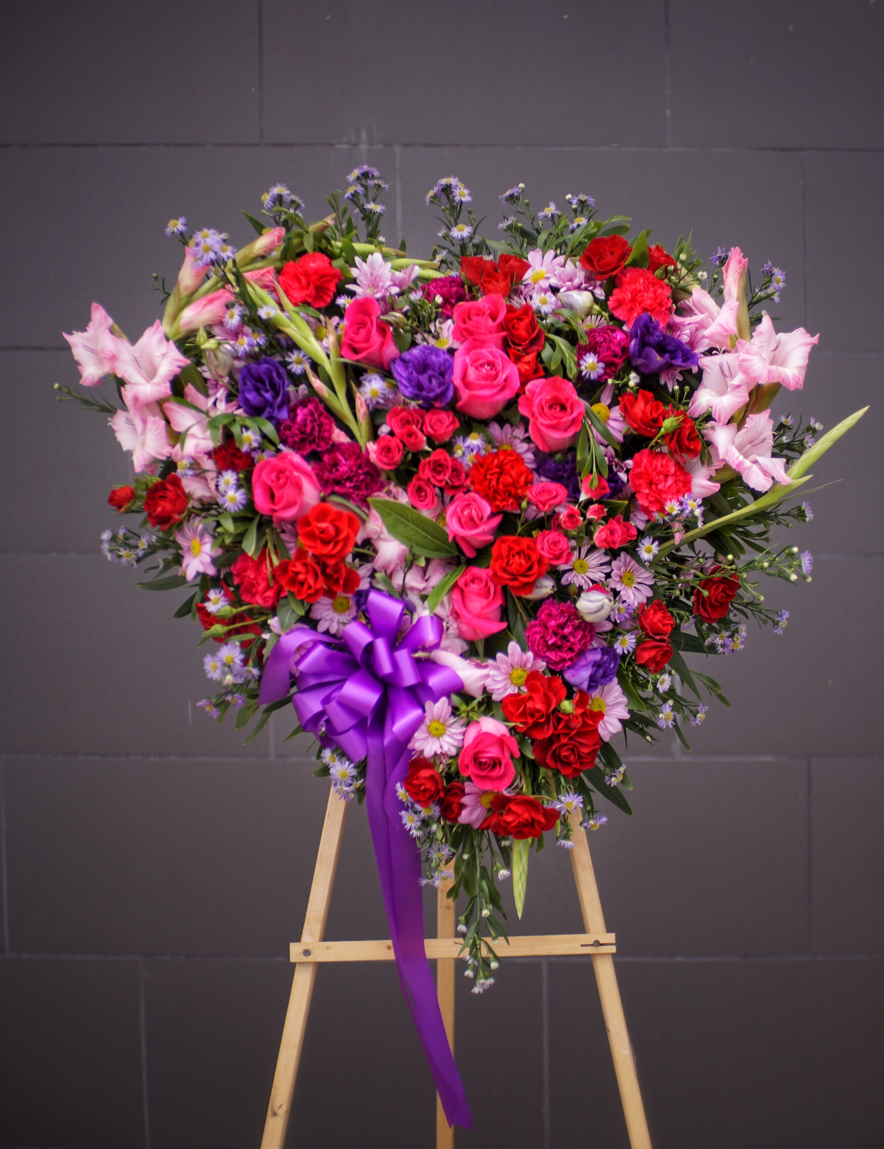 Heart-shaped floral spray with pink and red roses on an easel
