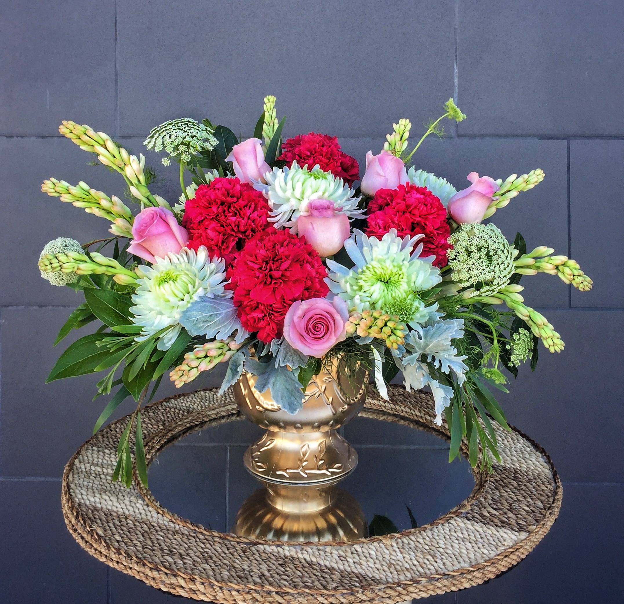 Mixed bouquet in a gold vase with pink roses and red carnations