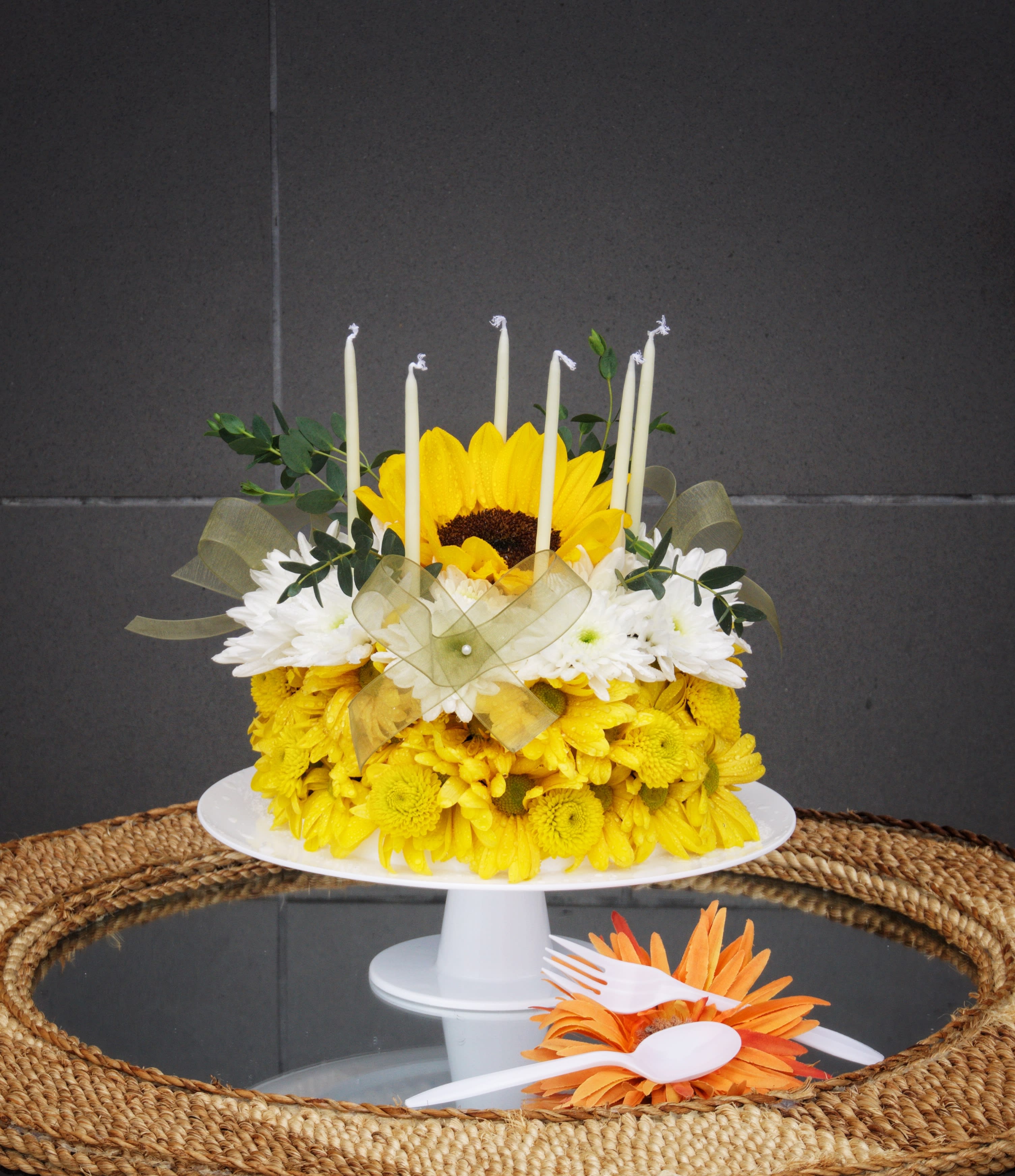 Yellow and white flower cake with candles on a white stand