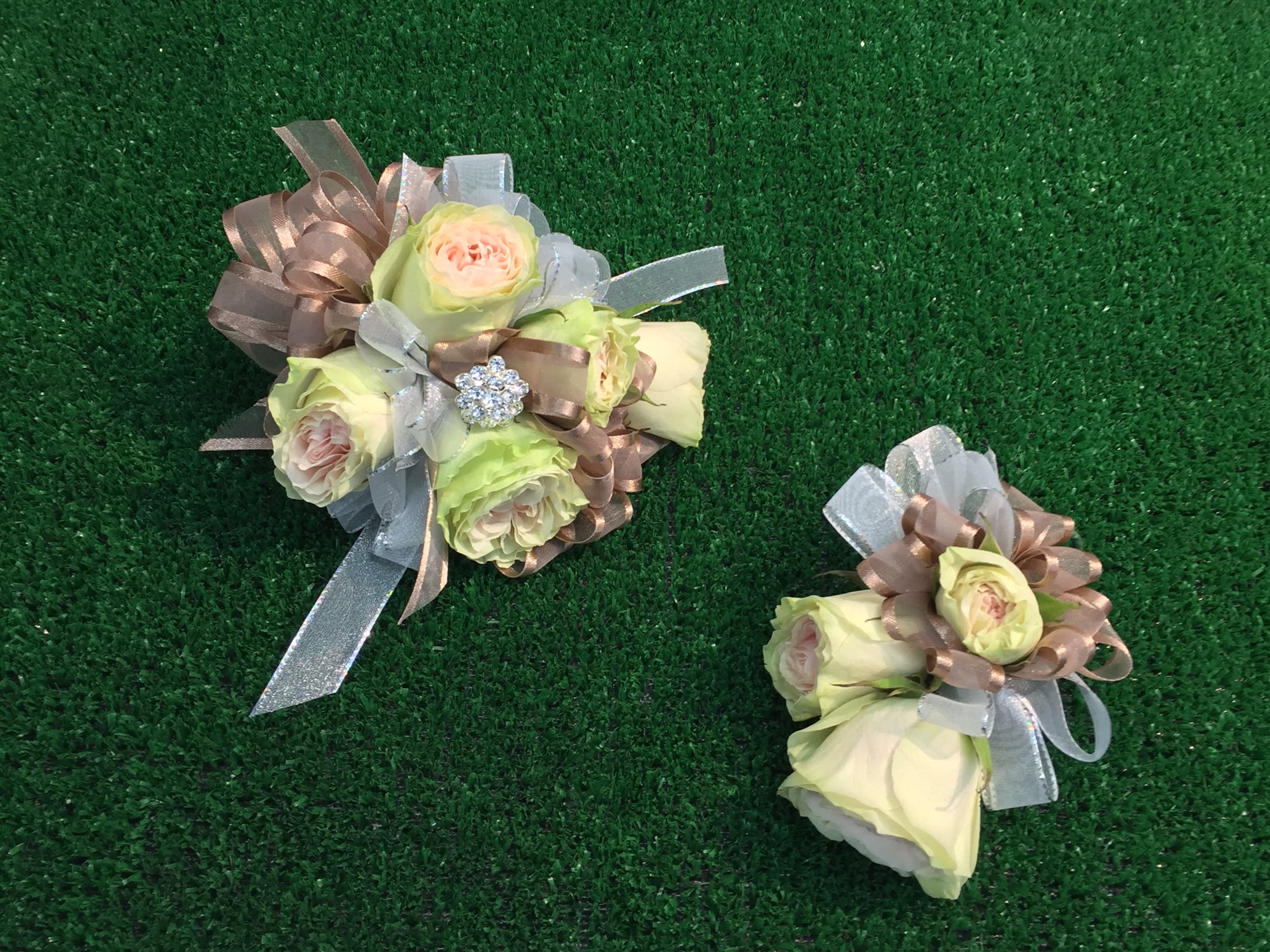 Two small rose bouquets with ribbon bows on green turf