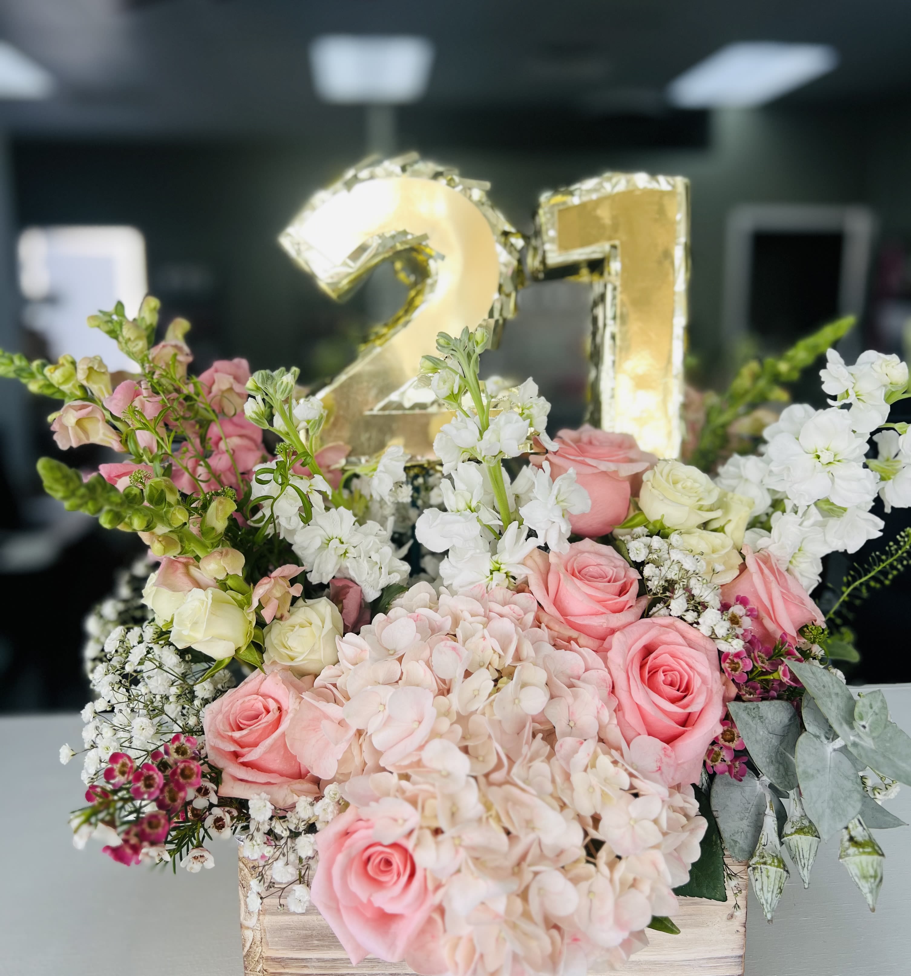 Pink and white floral arrangement with a gold "21" balloon