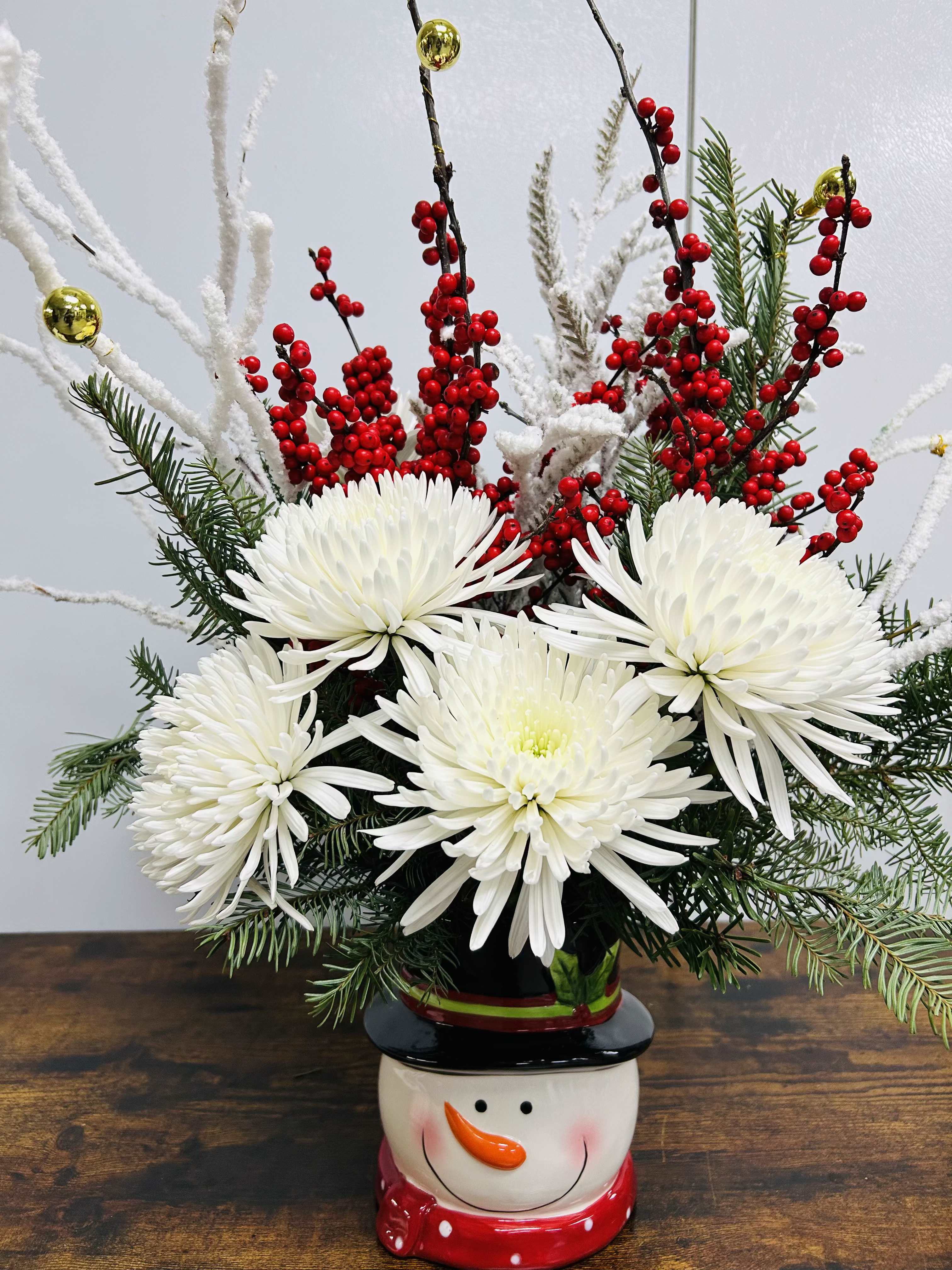 White chrysanthemum arrangement in a snowman vase with red berries