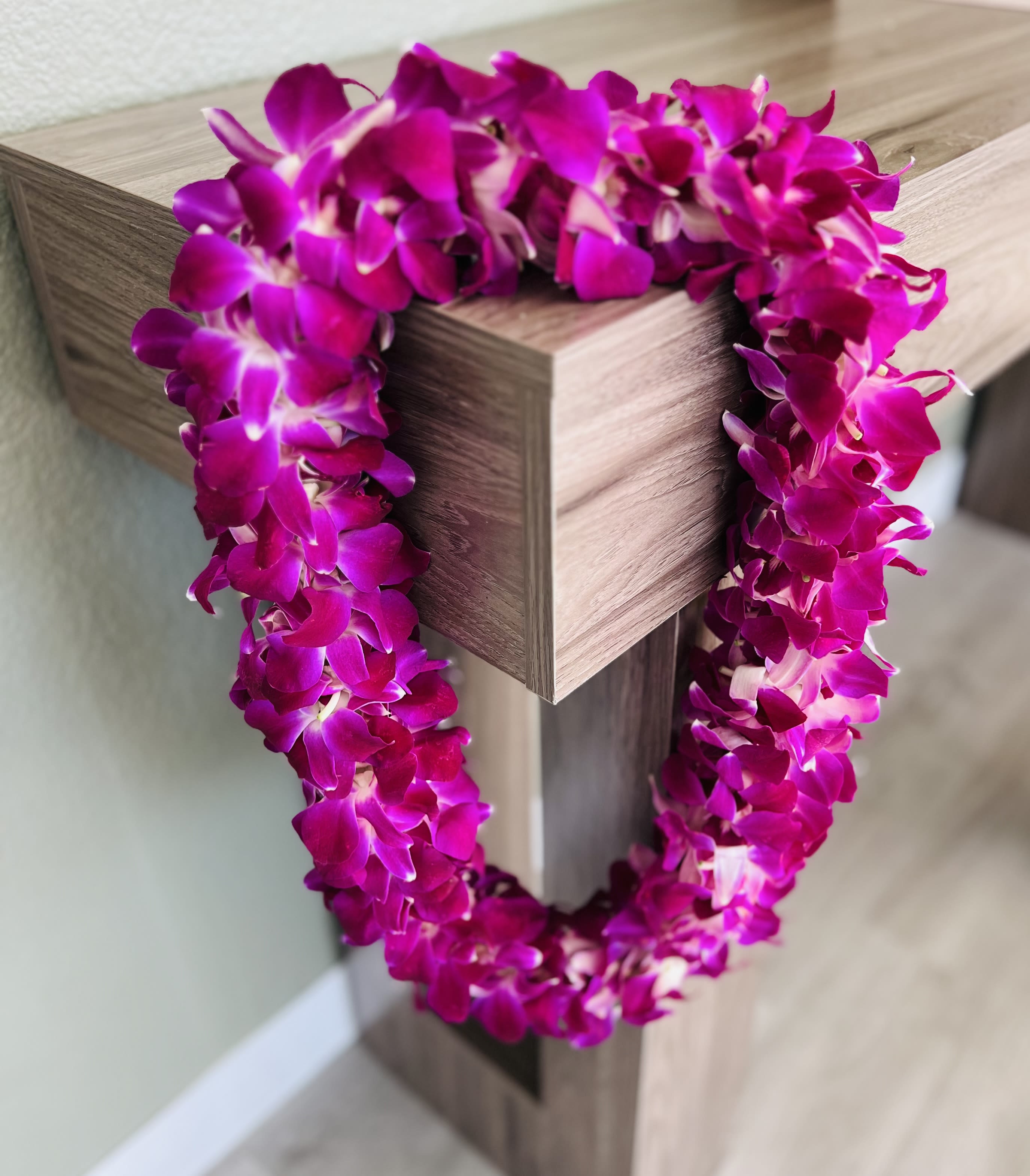 Magenta orchid lei draped over a wooden post