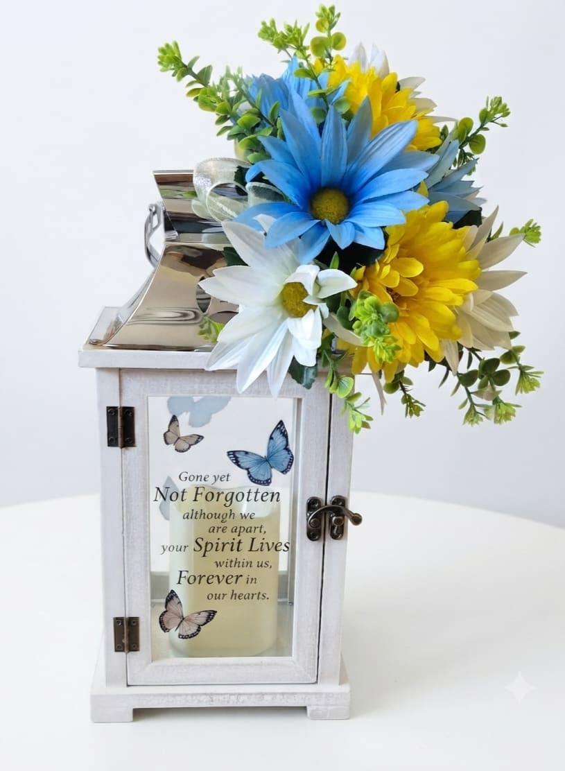 White memorial lantern with blue and yellow daisies and a remembrance message