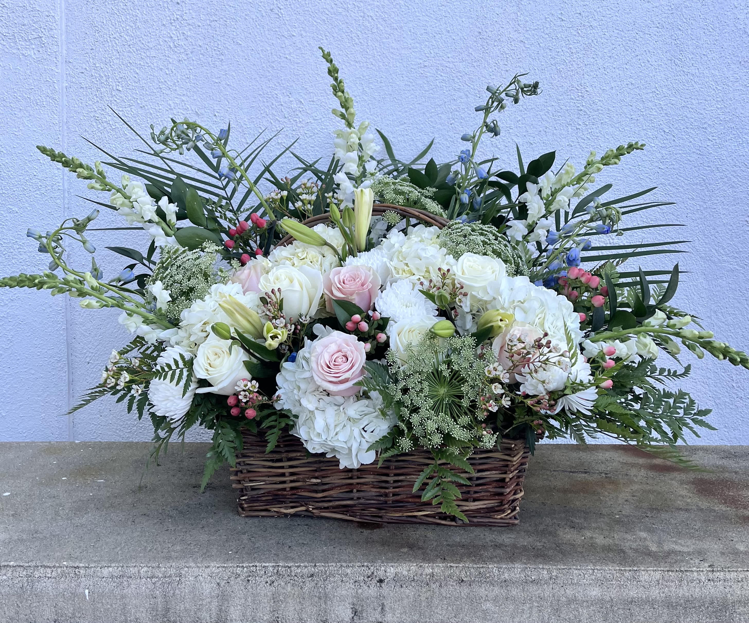 Large basket arrangement of white and pale pink flowers with tall accents
