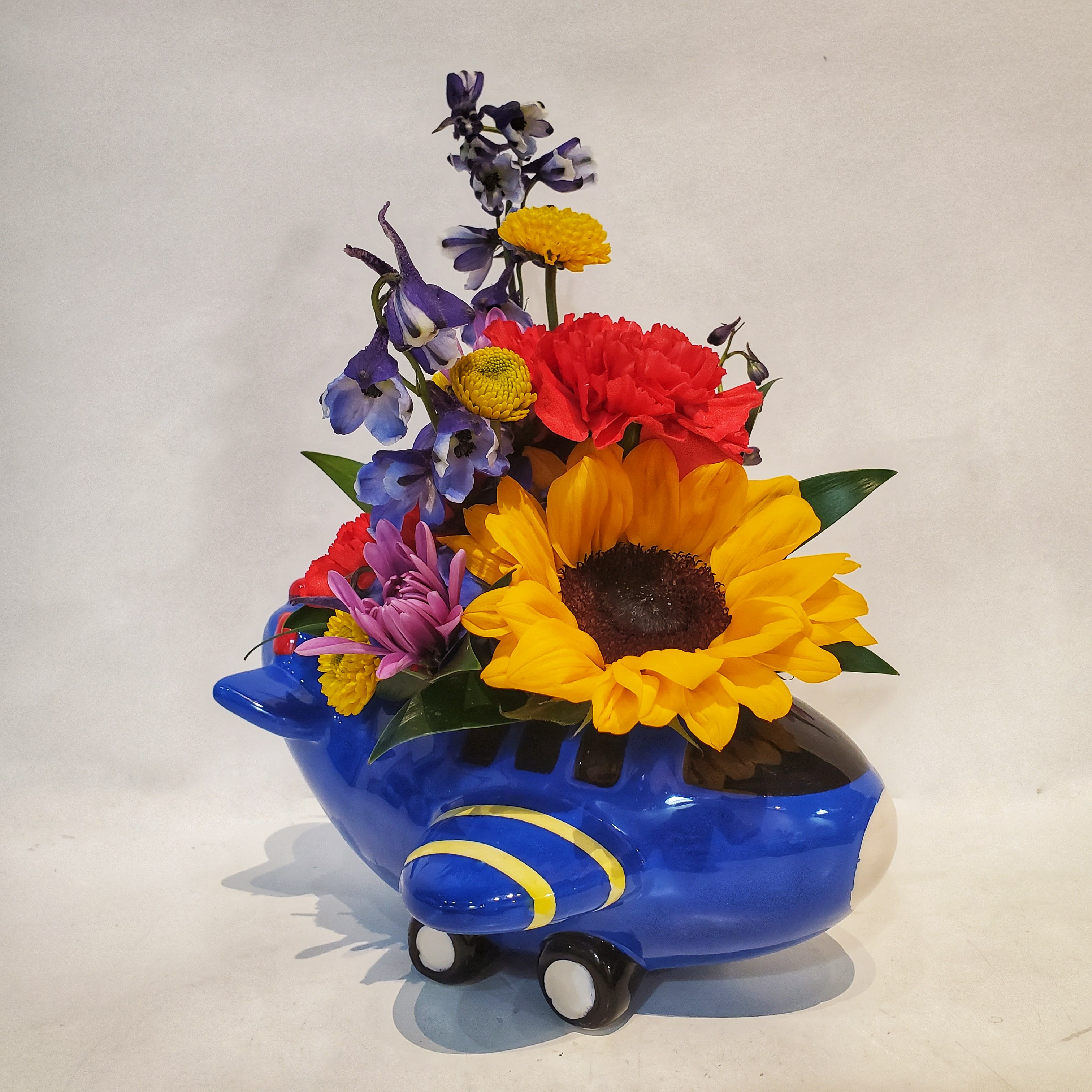 Colorful flowers arranged in a blue airplane-shaped container