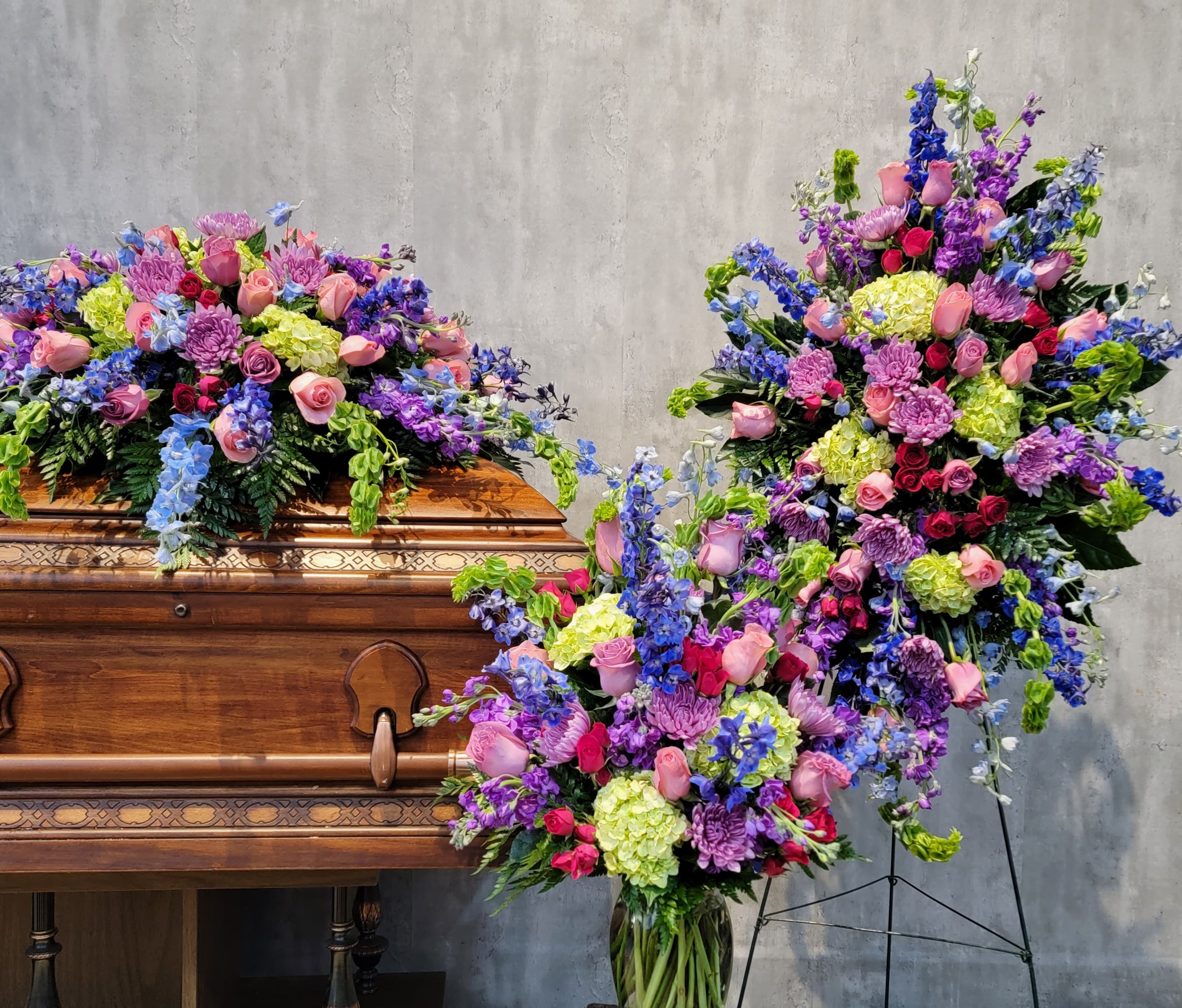 Large floral sprays on and beside a wooden casket