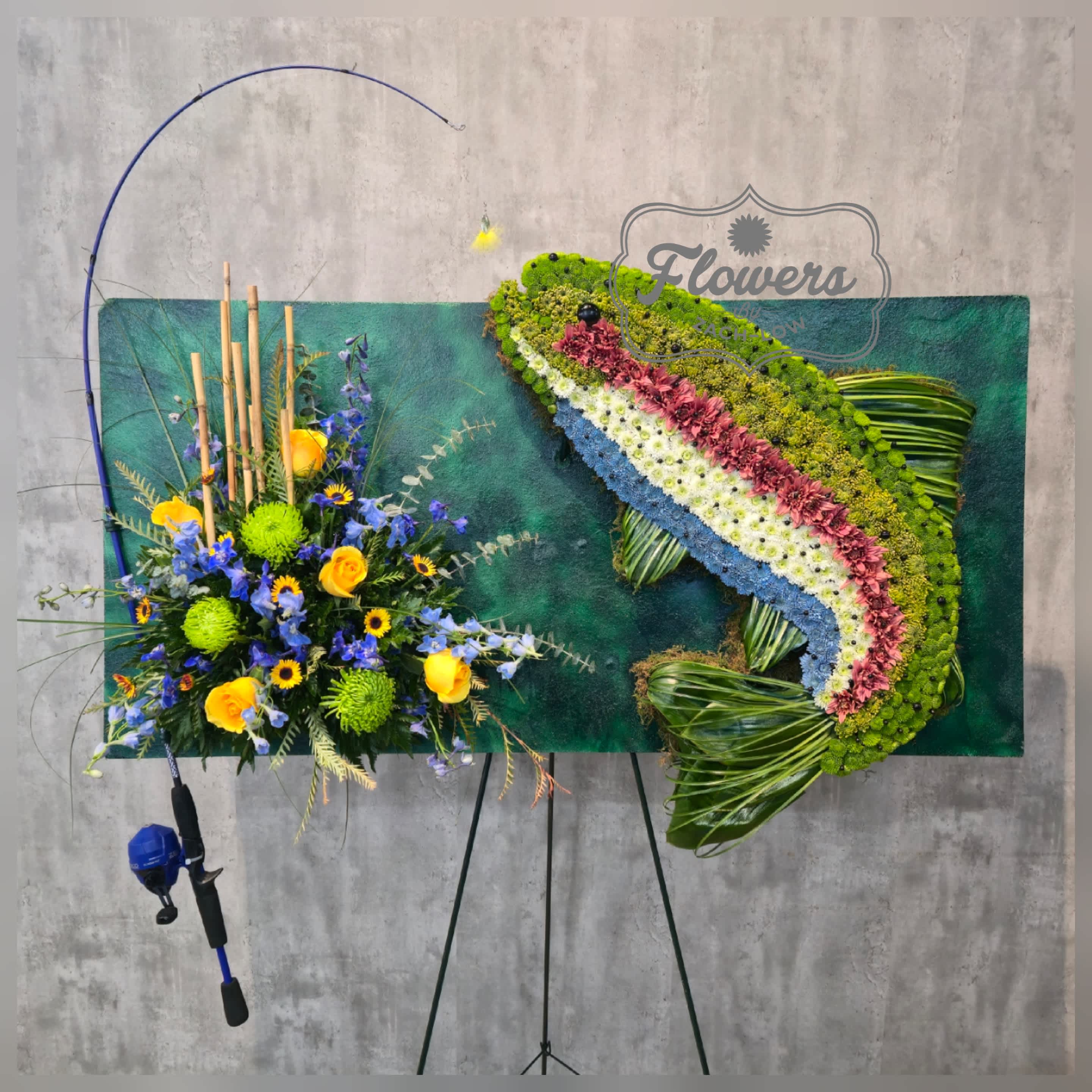 Large floral display with blue, yellow, and green flowers on an easel.