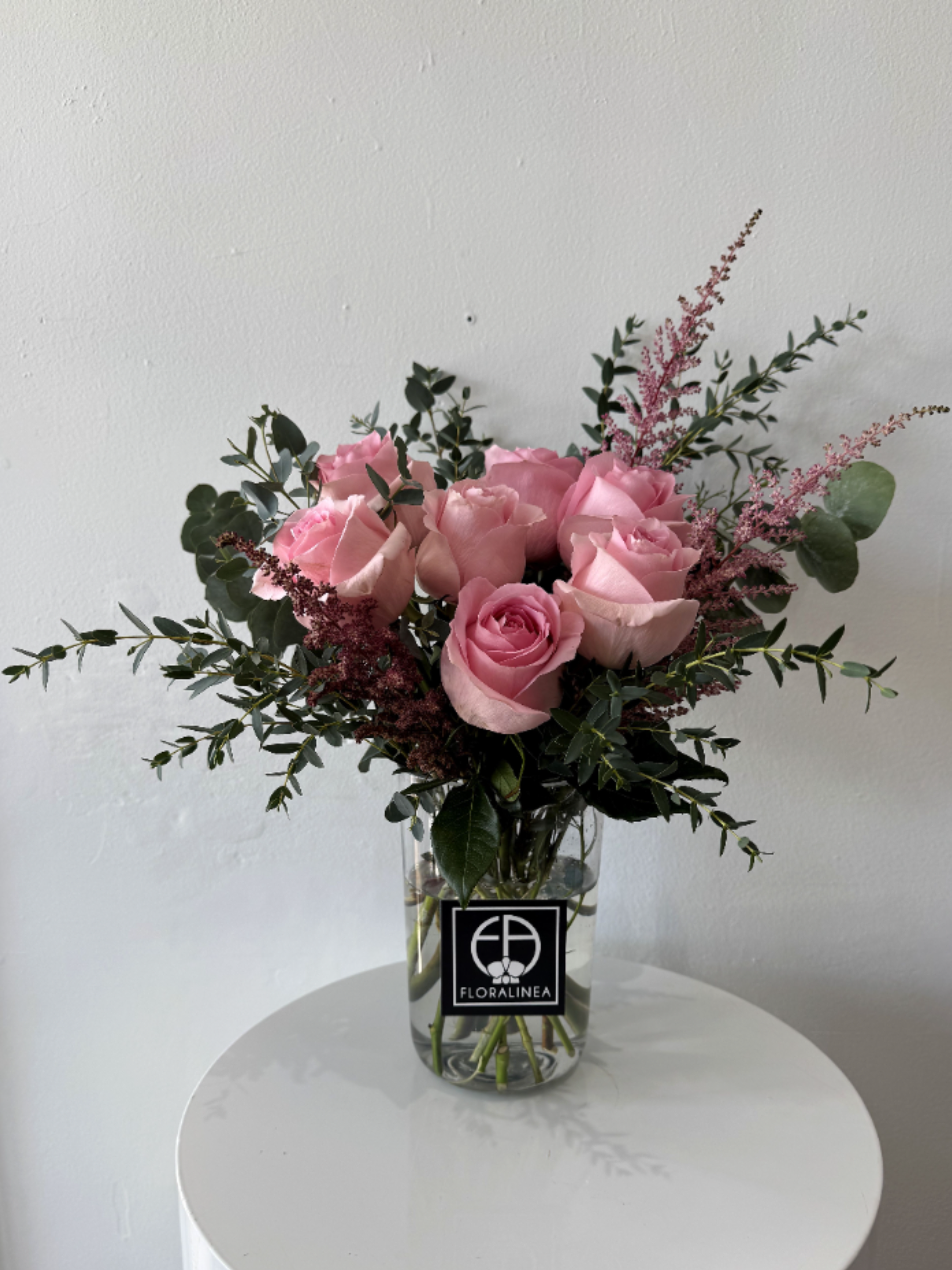 Pink roses in a clear glass vase with airy greenery