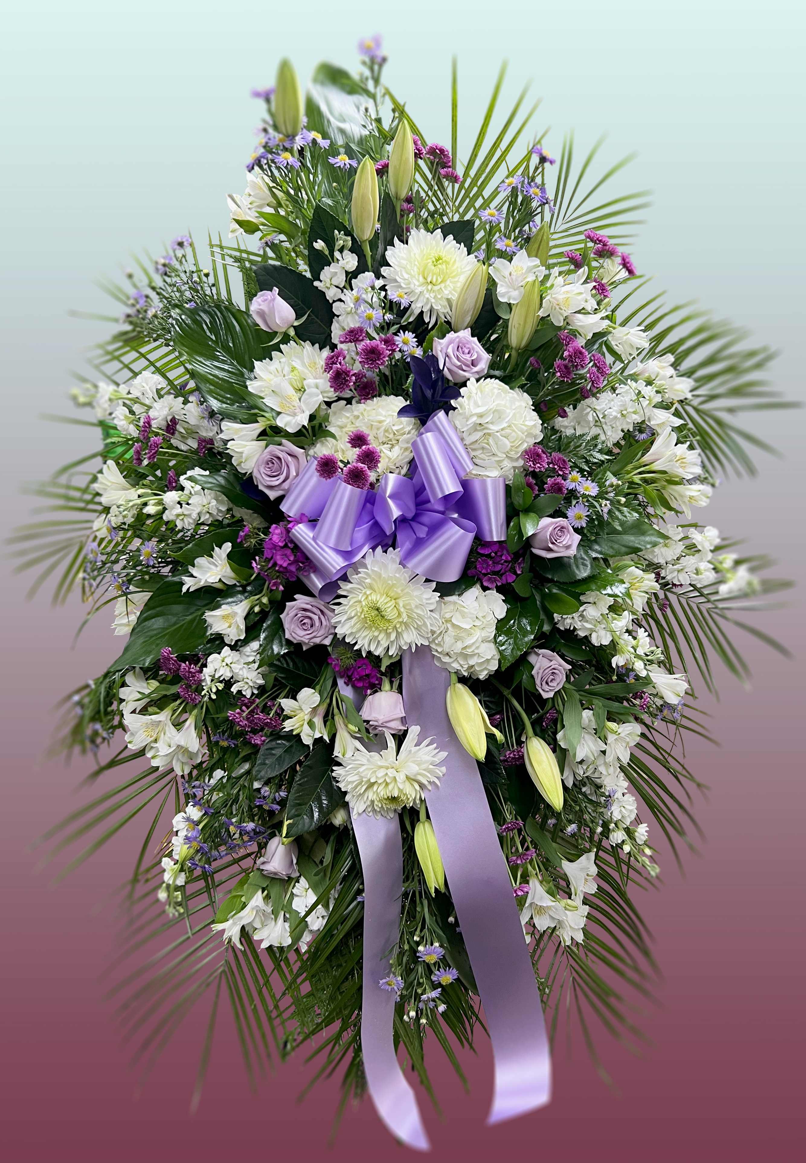 Not Forgotten - This easel spray is composed of lavender roses, mums, oriental lilies, dianthus, and buttons.  