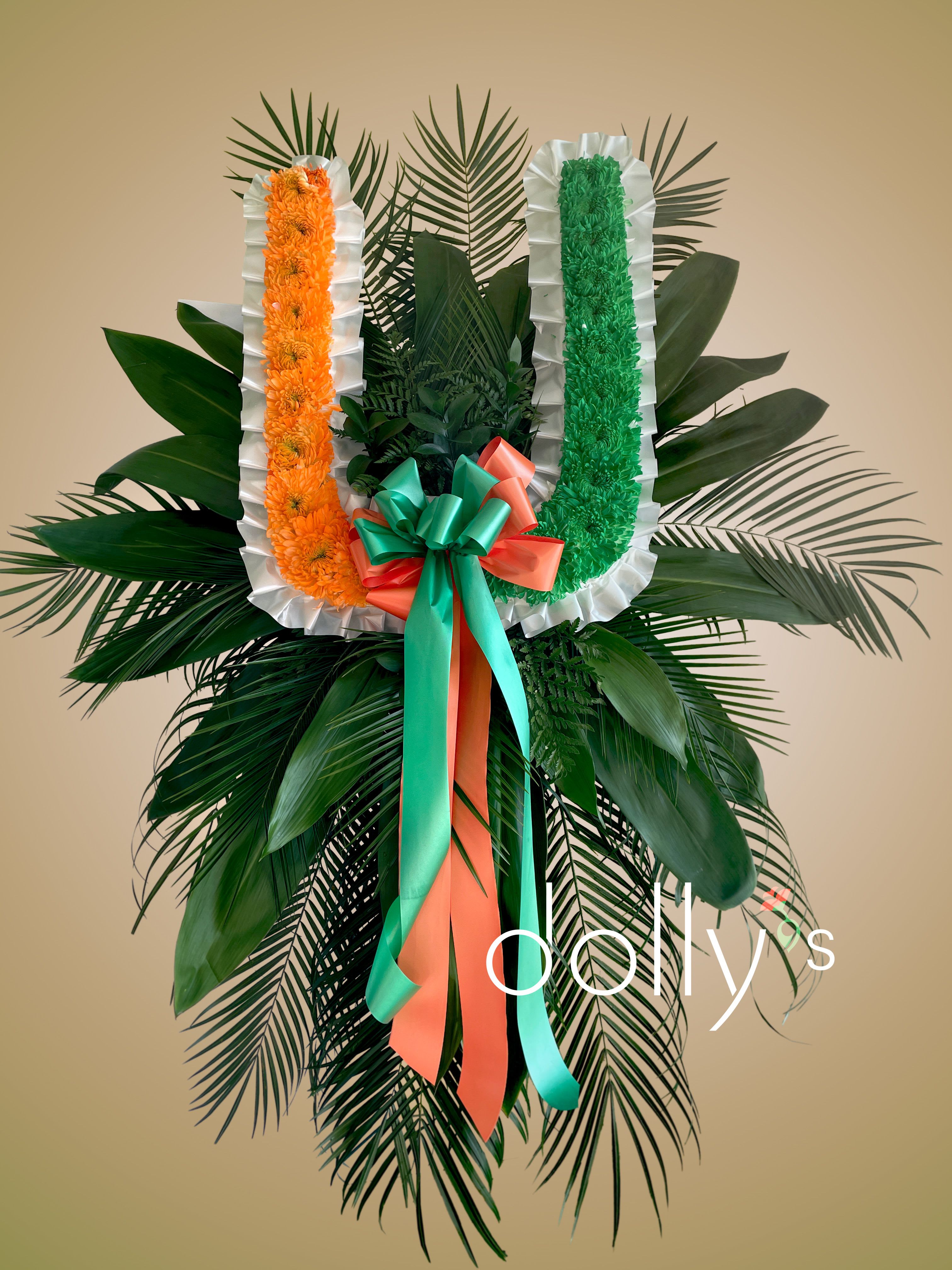 Large standing floral tribute with orange and green garlands and ribbon bow