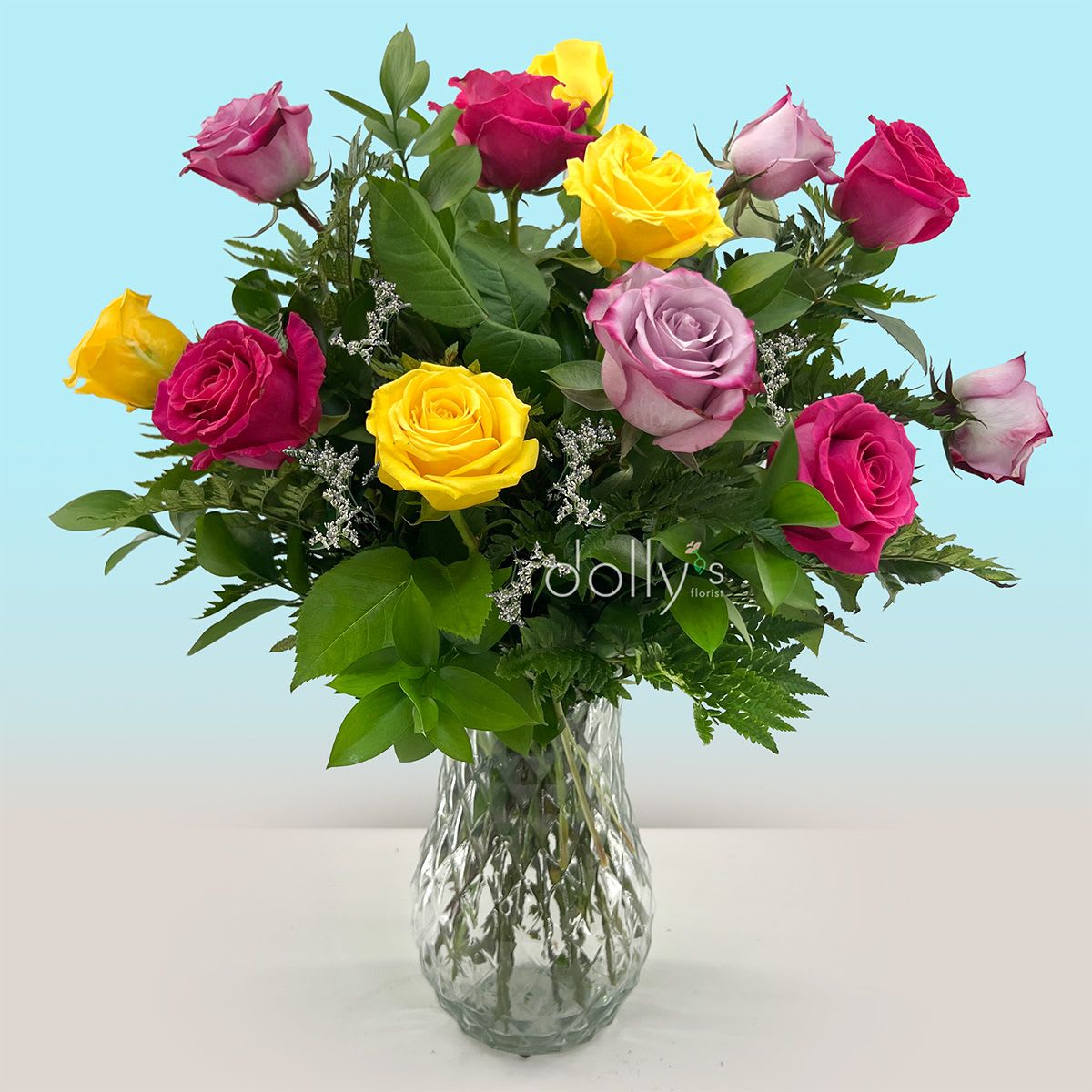 Classic Dozen Mixed Color Long-Stem Rose Bouquet  - Bright, long-stem roses in mixed colors  create a cheerful, garden-fresh statement for an anniversary, "I'm sorry" peace offering, or a warm Labor Day table centerpiece. This mixed-color long-stem rose bouquet in a clear glass vase reads as both classic and celebratory, the kind of arrangement that makes the person you're thinking of feel genuinely noticed and appreciated.  Twelve long-stem assorted-color roses are gathered with fine white filler blooms and fern-like greenery for an airy, rounded silhouette; some stems sit slightly taller for a layered, natural look. The clear faceted glass vase keeps the focus on the saturated and pastel petals, while abundant foliage adds depth and texture - ideal for Mother's Day, Valentine's Day, thank-you gestures, congratulations, or Best Friends Day.  Arranged by the designer and delivered ready to display, this bouquet requires no assembly. For longer enjoyment, refresh the water every few days and recut stems at an angle; available as one standard size of 12 long-stem roses unless you request a different size.