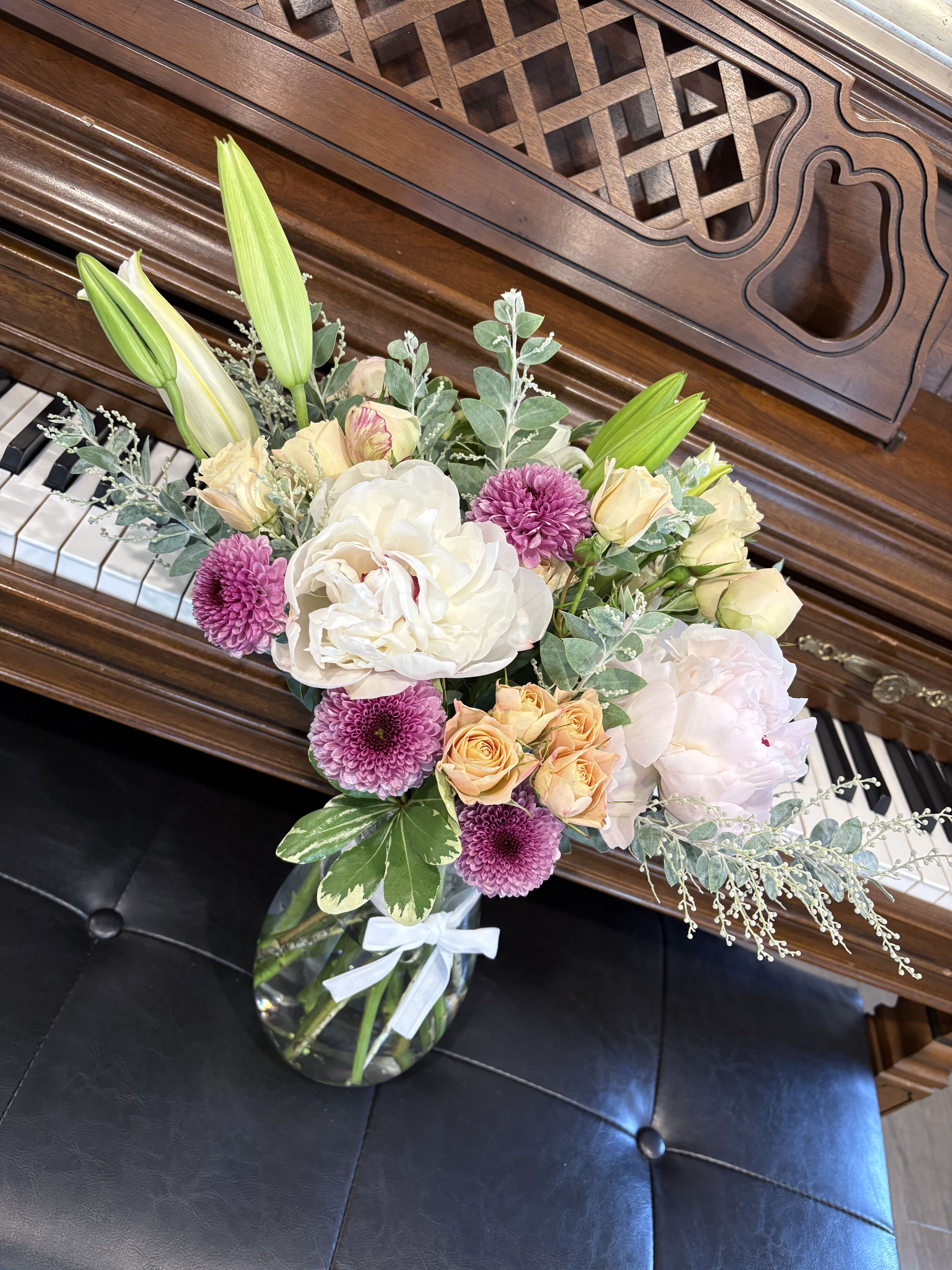 Bouquet of lilies, roses, and purple mums in a glass vase