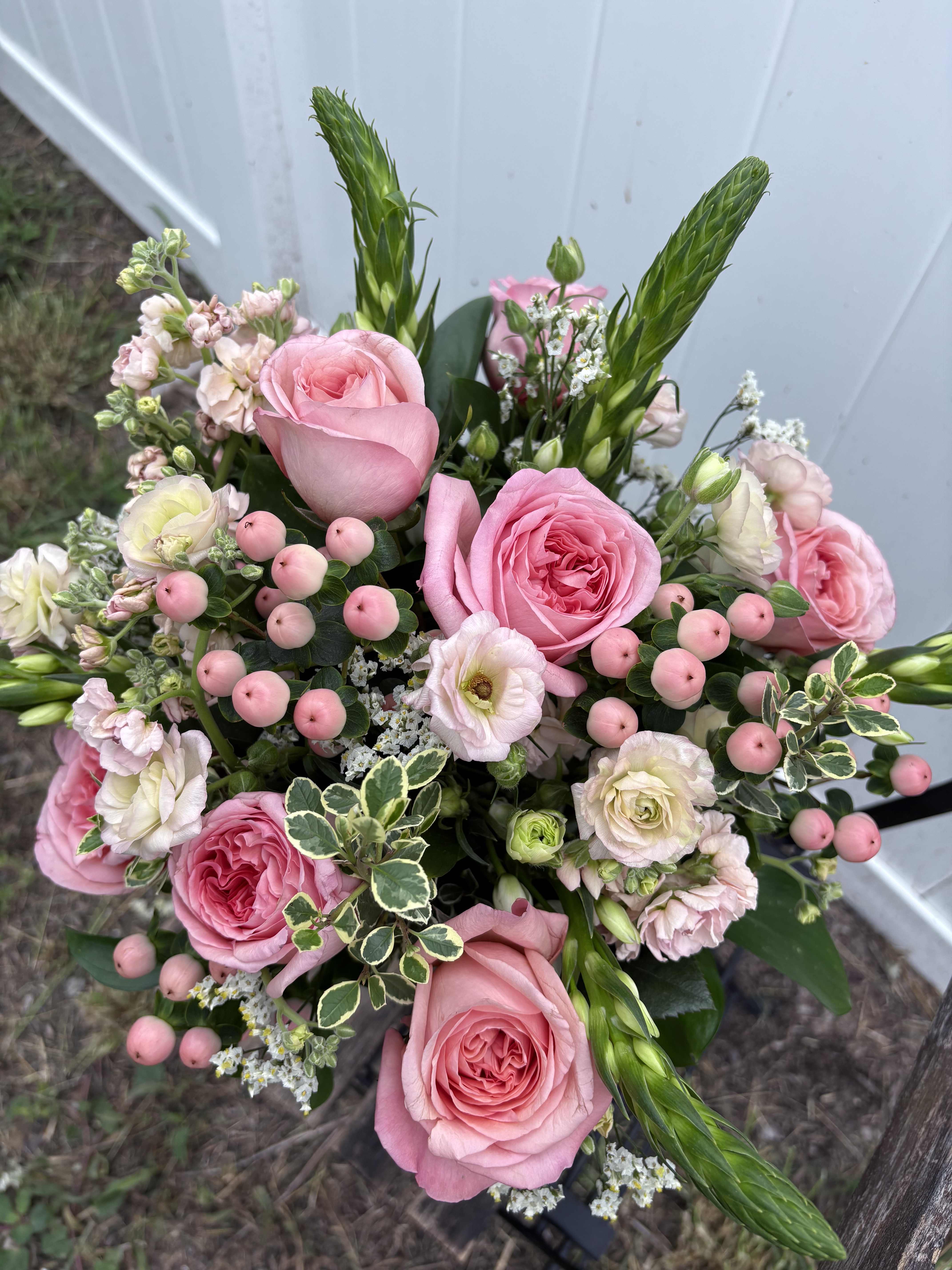 Pink roses and mixed blooms arranged in a hand-tied bouquet