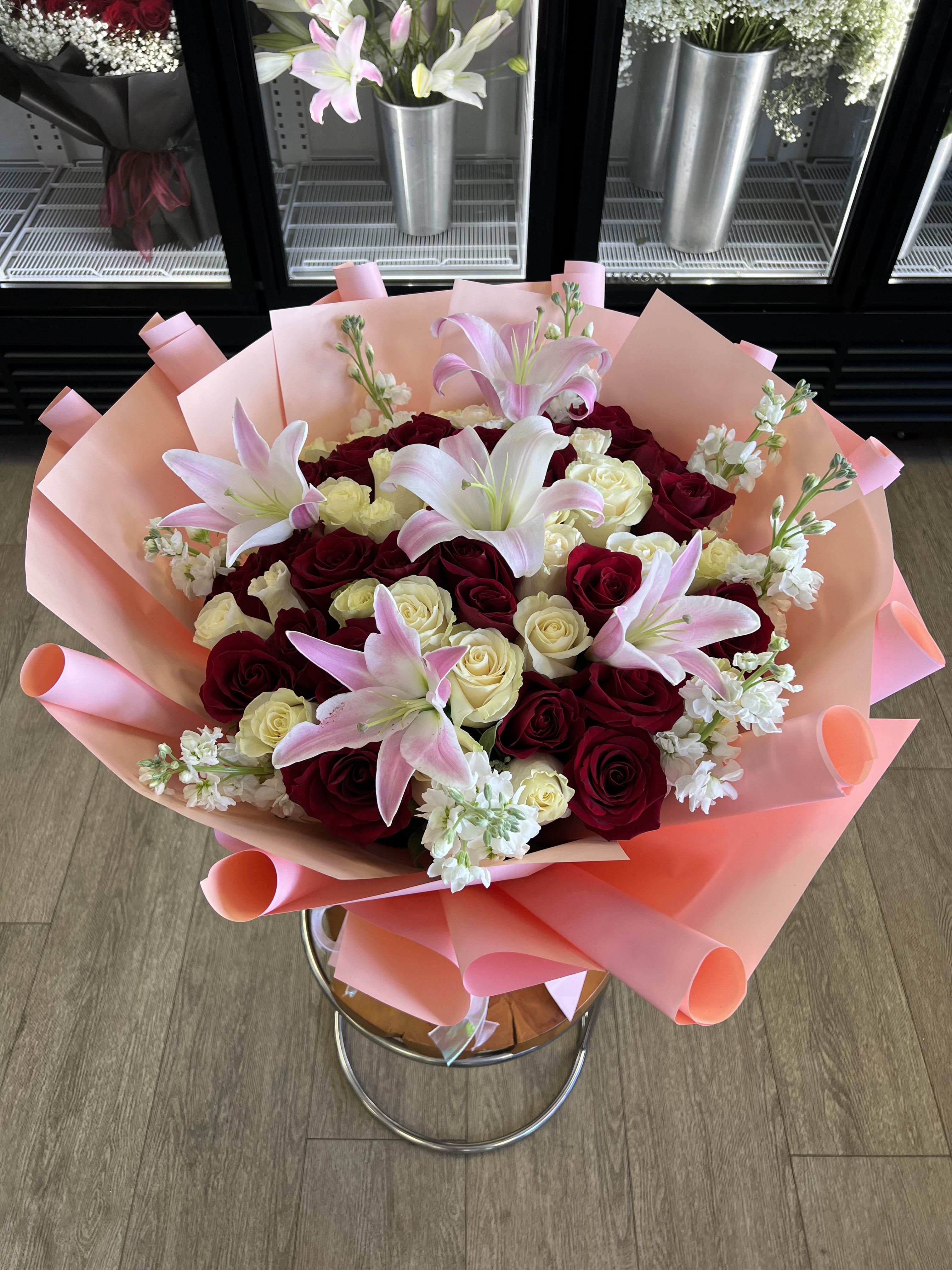 Princess Alla - A lush cluster of deep red and ivory roses framed by pink-and lilies-this Princess Alla flower arrangement is a romantic bouquet perfect for an anniversary, Valentine's Day, or any moment you want the person you're thinking of to feel truly cherished. The strong contrast between the dramatic red centers and the soft blush tones gives the arrangement both a classic romantic energy and a tender, celebratory feel.