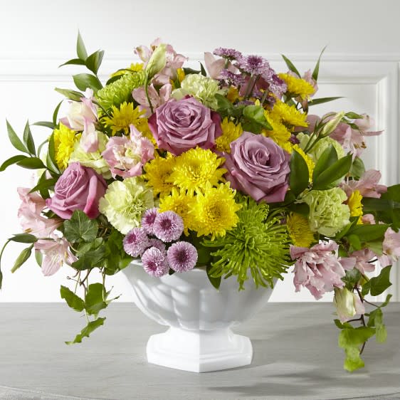 Mixed bouquet of pink roses and yellow flowers in a white vase