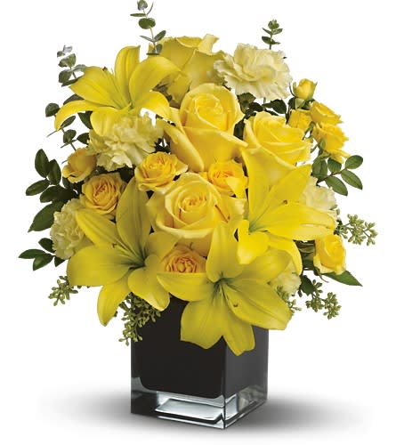 Yellow roses and lilies arranged in a square glass vase