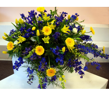 Large bouquet of yellow and blue flowers in a white container