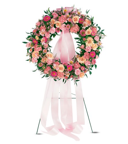 Pink and peach floral wreath on a stand with a long pink ribbon