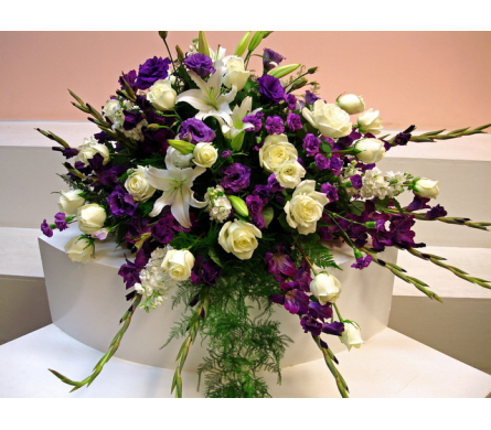 White lilies and cream roses with purple flowers in a large arrangement