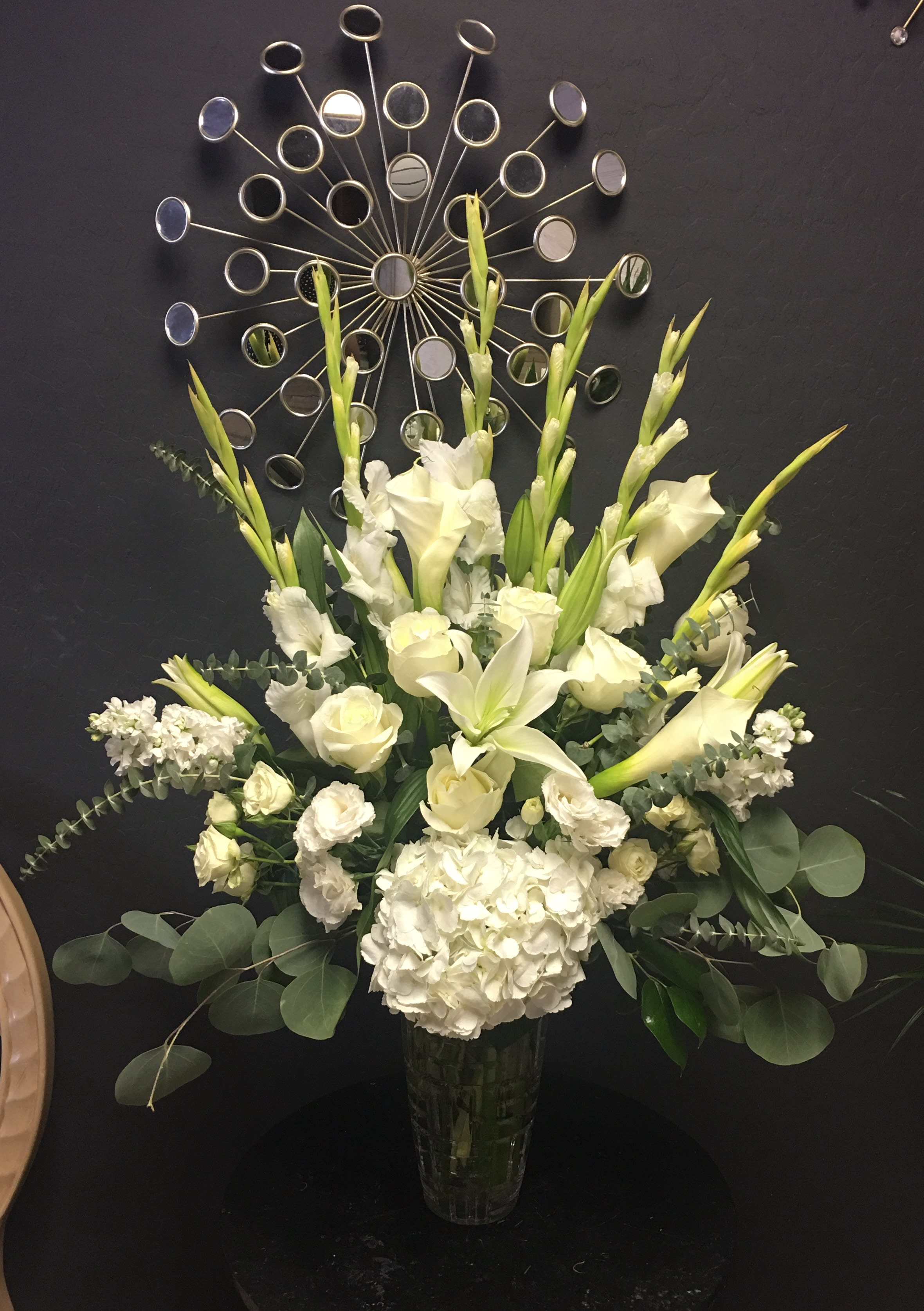 White floral arrangement in a glass vase with tall blooms and greenery