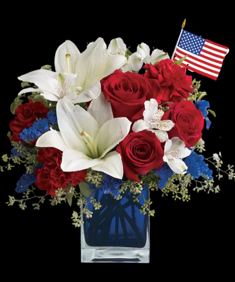 Red roses and white lilies in a blue vase with a small American flag
