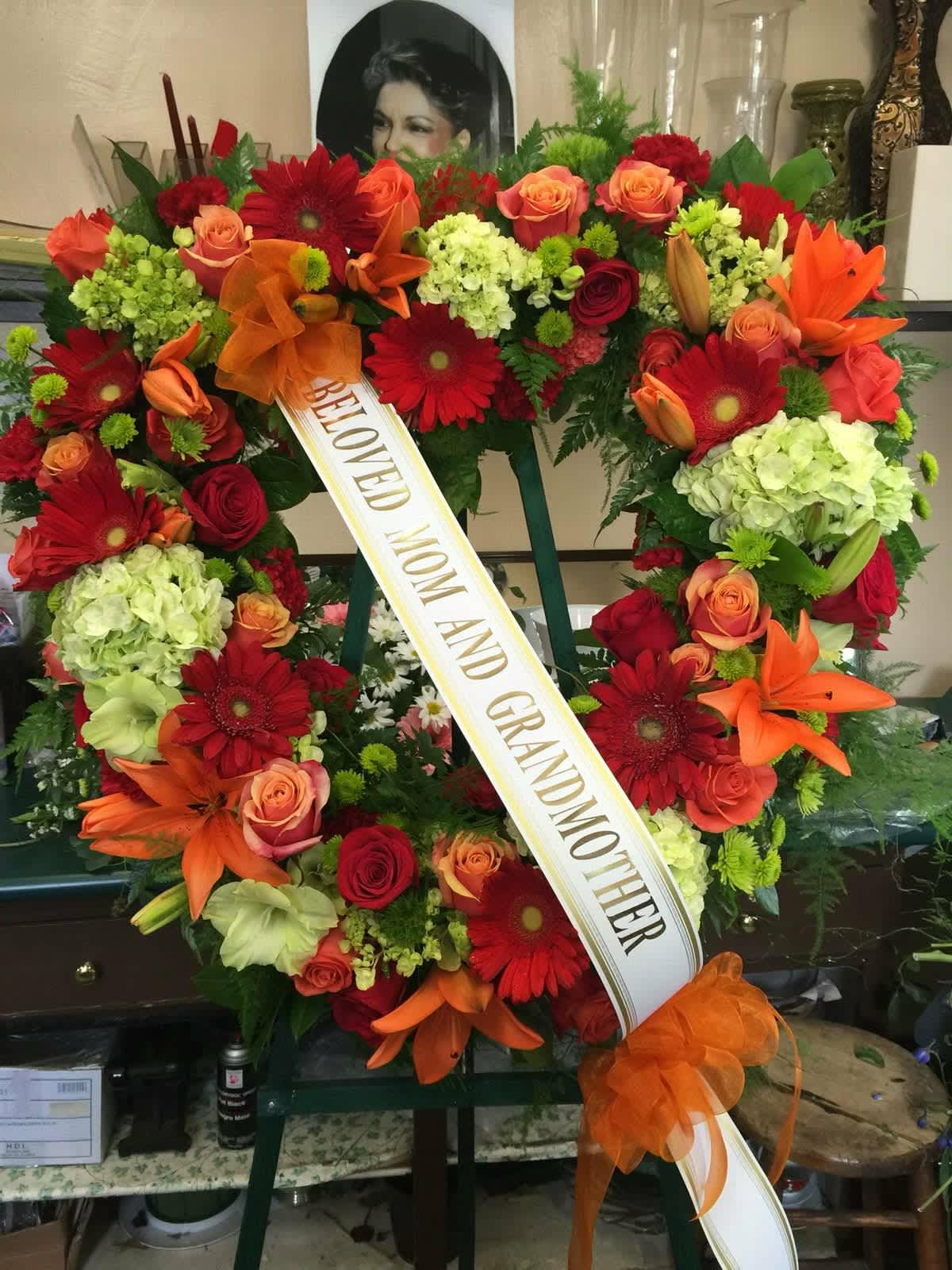 Heart-shaped floral wreath with a memorial ribbon and orange bow