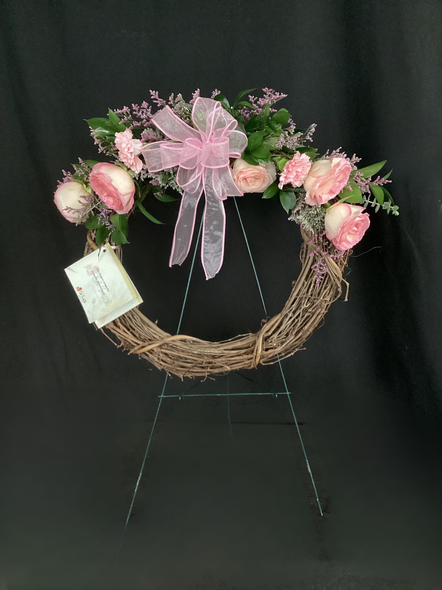 Pink rose wreath with a large ribbon bow on a grapevine frame