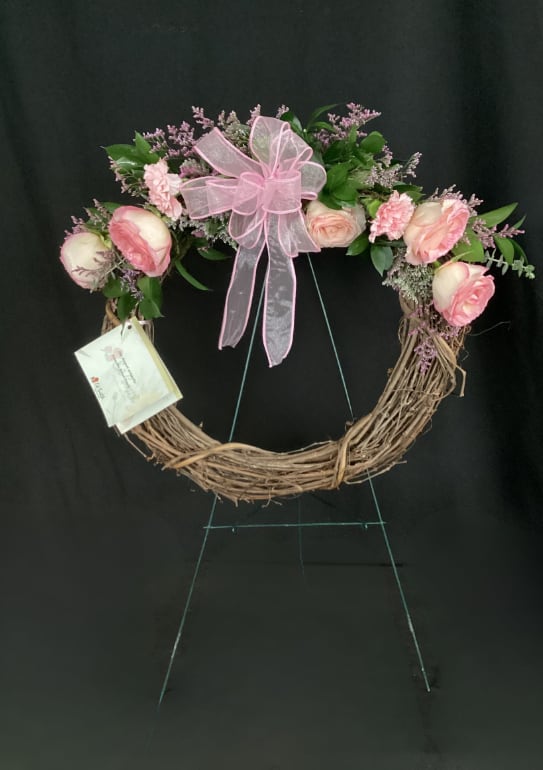 Pink floral wreath with a ribbon bow on a twig base