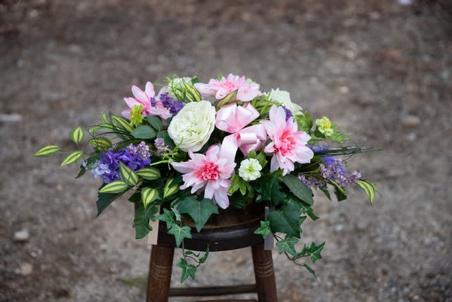 Pink and white floral arrangement with purple accents in a low container