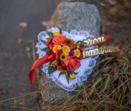 Heart-shaped floral tribute with red and yellow roses and a red ribbon