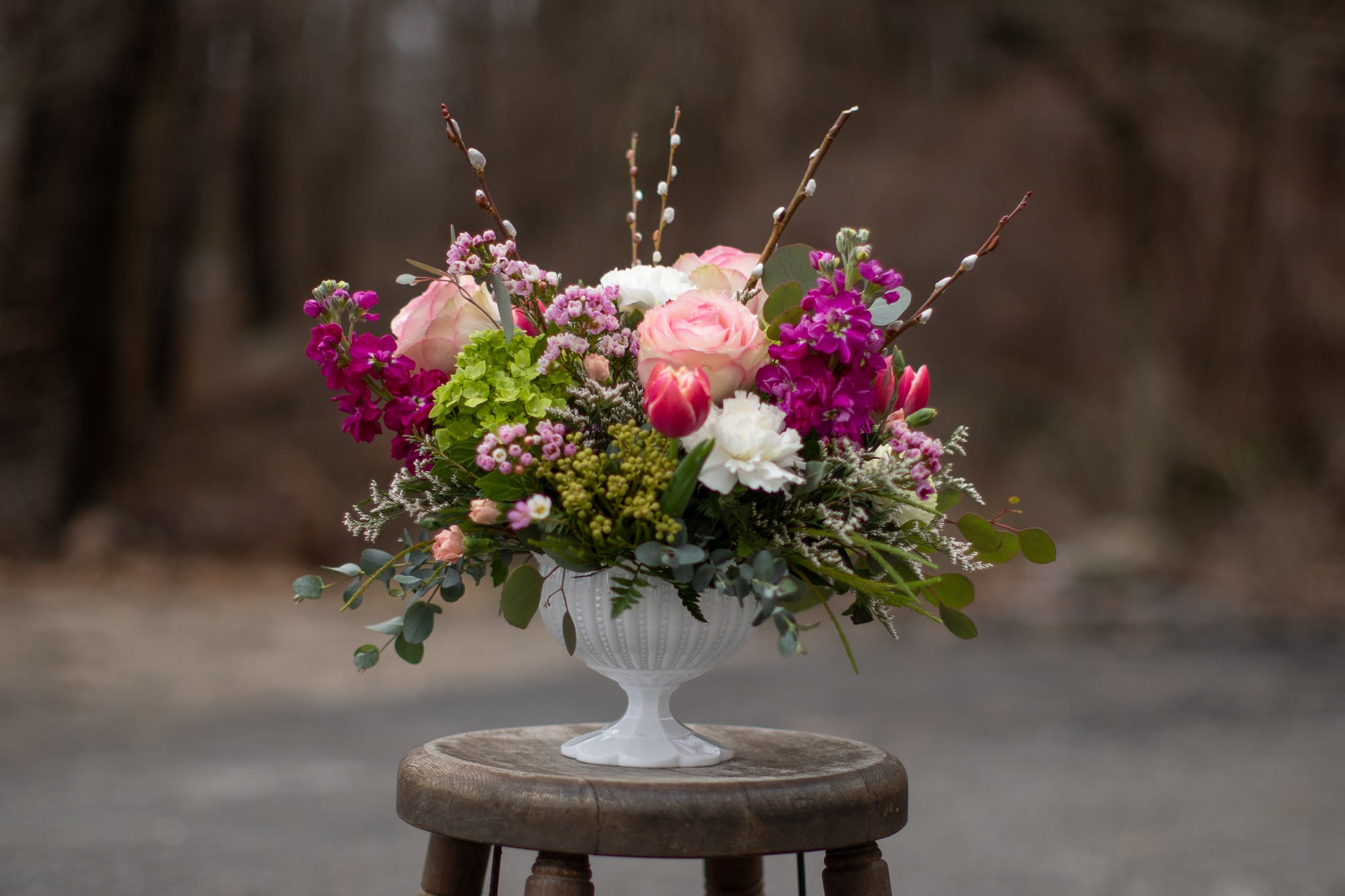 Pink and white floral arrangement in a white pedestal vase
