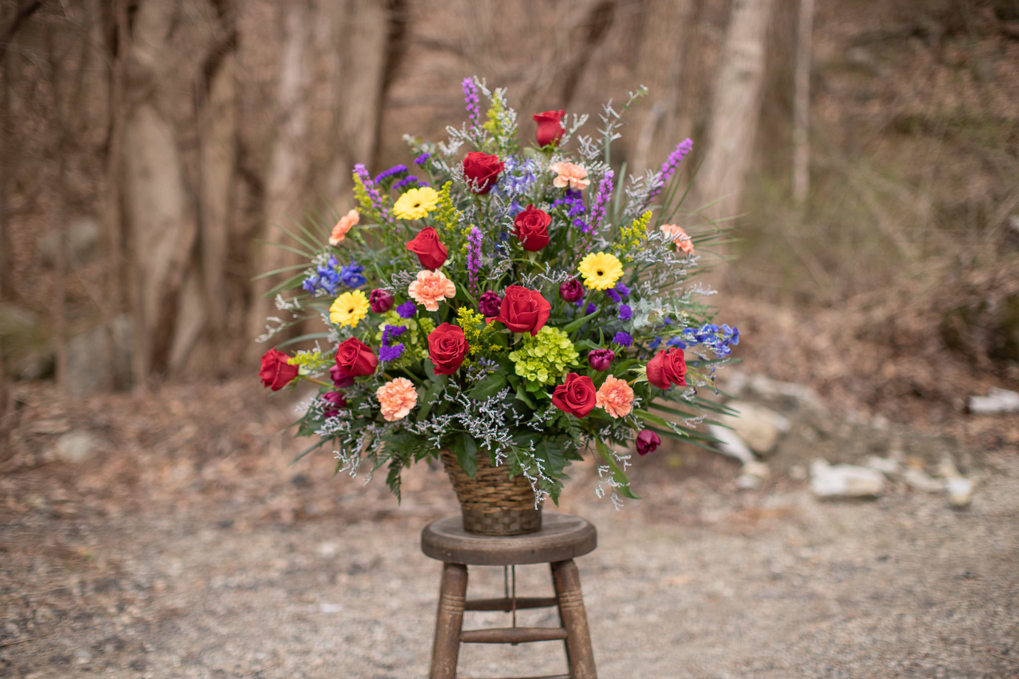 Mixed bouquet of roses, daisies, and carnations in a woven basket