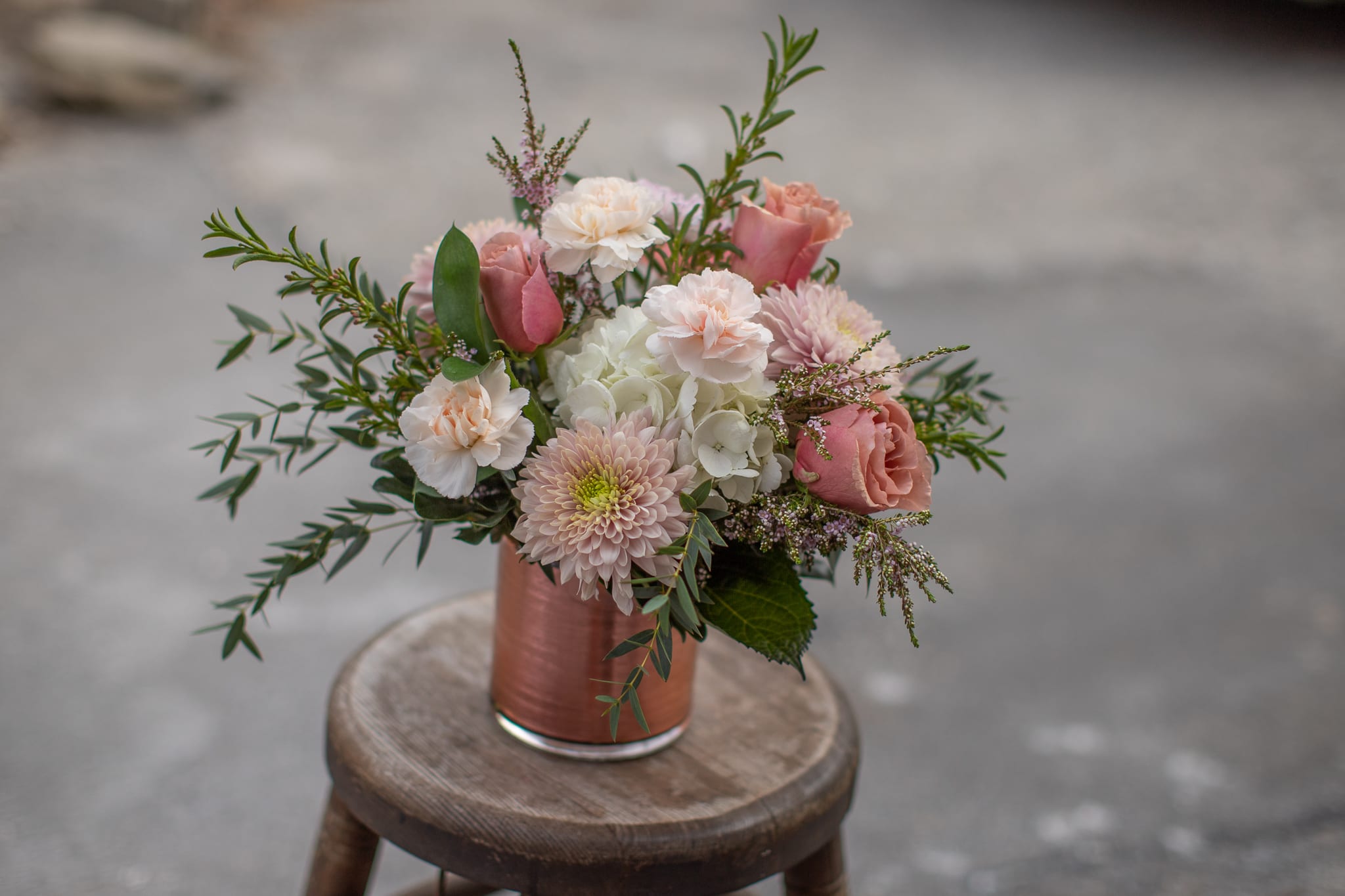 Pink and white bouquet in a copper vase on a stool