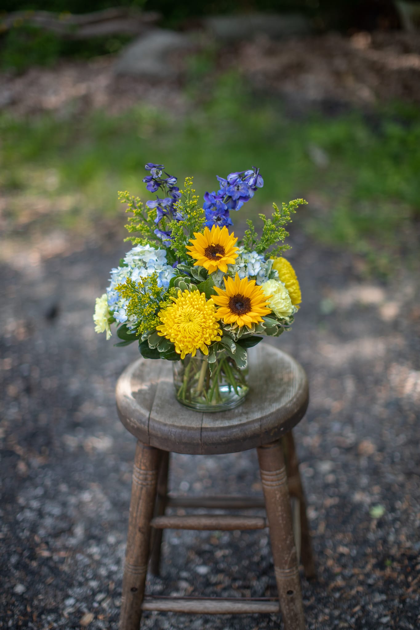 Mixed bouquet in a clear glass vase with yellow sunflowers and blue flowers