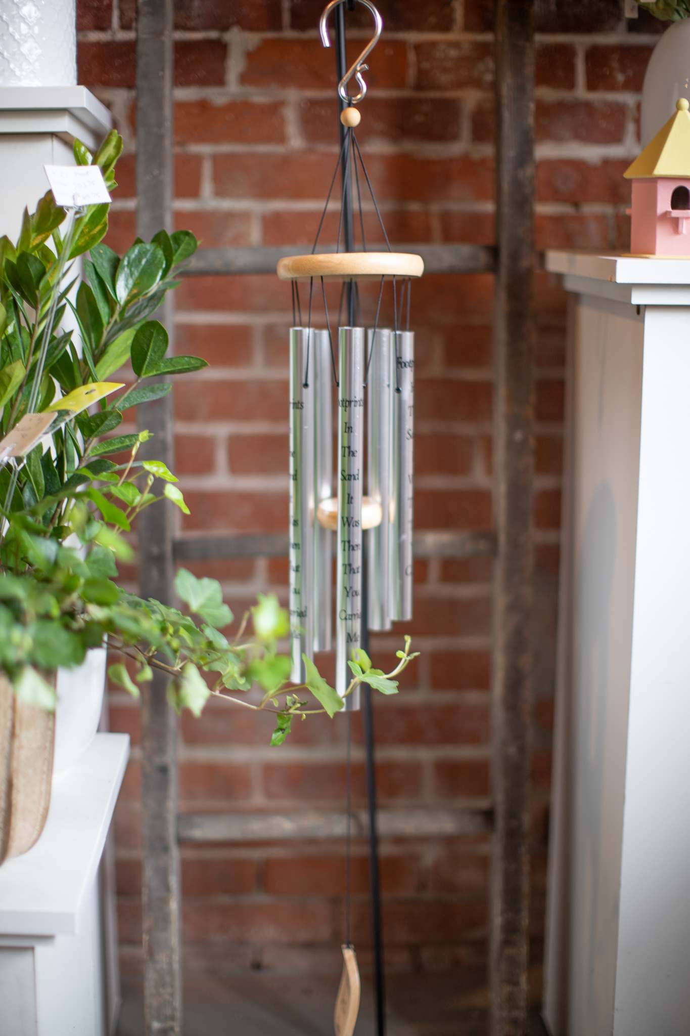 Hanging silver wind chime with a wooden top and black cords