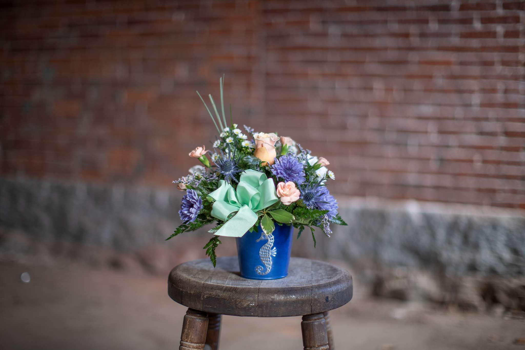 Mixed bouquet in a blue vase with a mint ribbon bow
