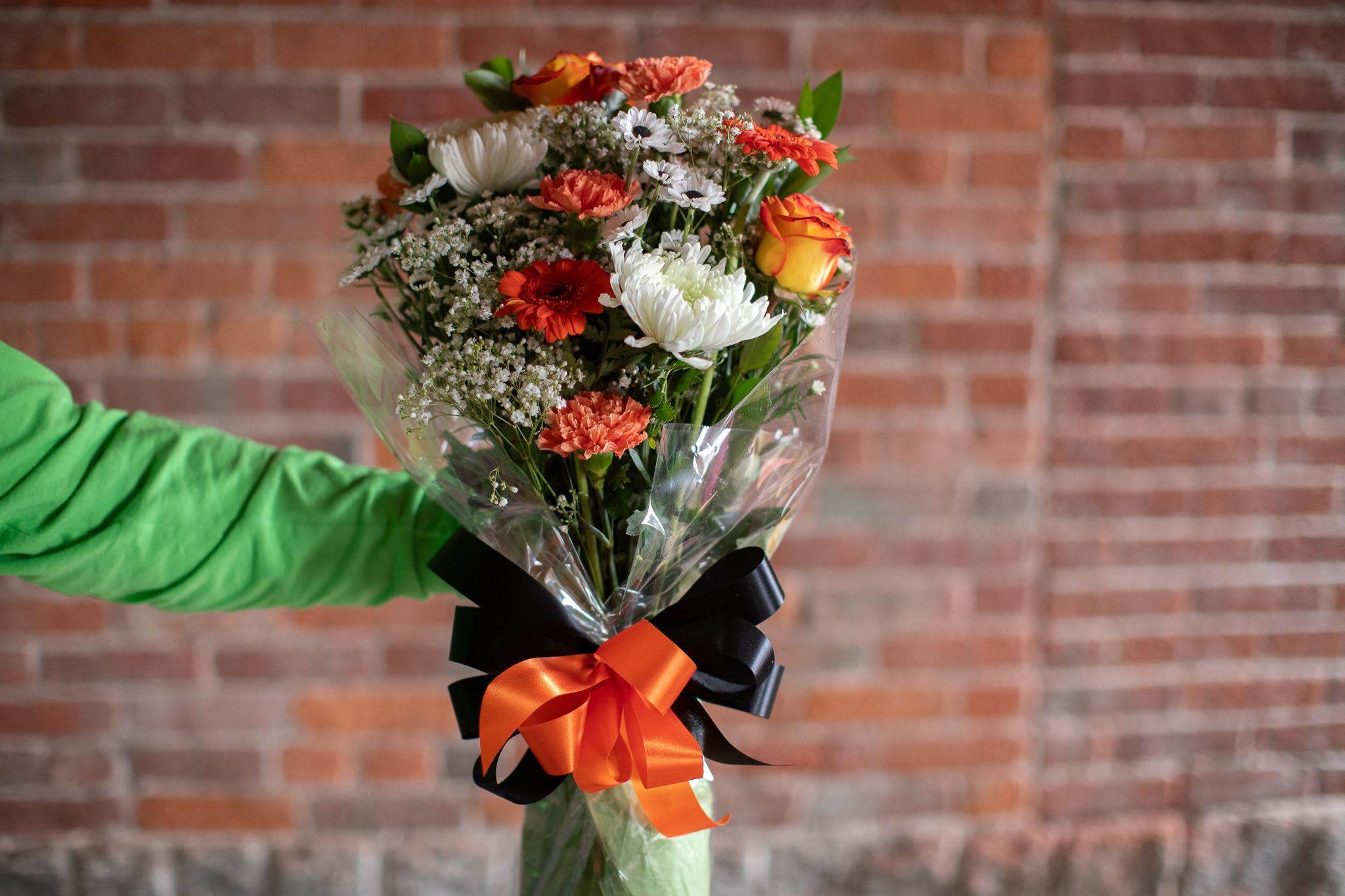 Mixed bouquet of orange, white, and red flowers wrapped in clear plastic
