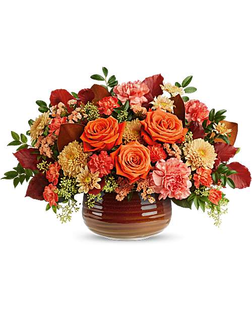 Orange roses and mixed fall flowers arranged in a brown vase