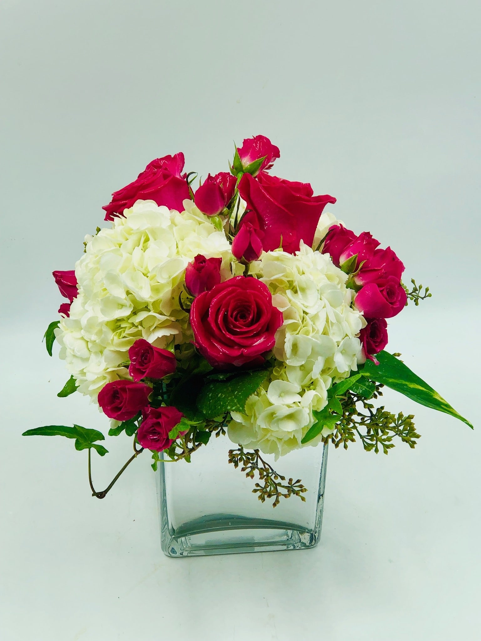 Pink roses and white hydrangeas arranged in a clear glass vase