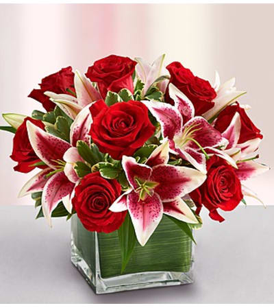 Red roses and pink lilies arranged in a square glass vase