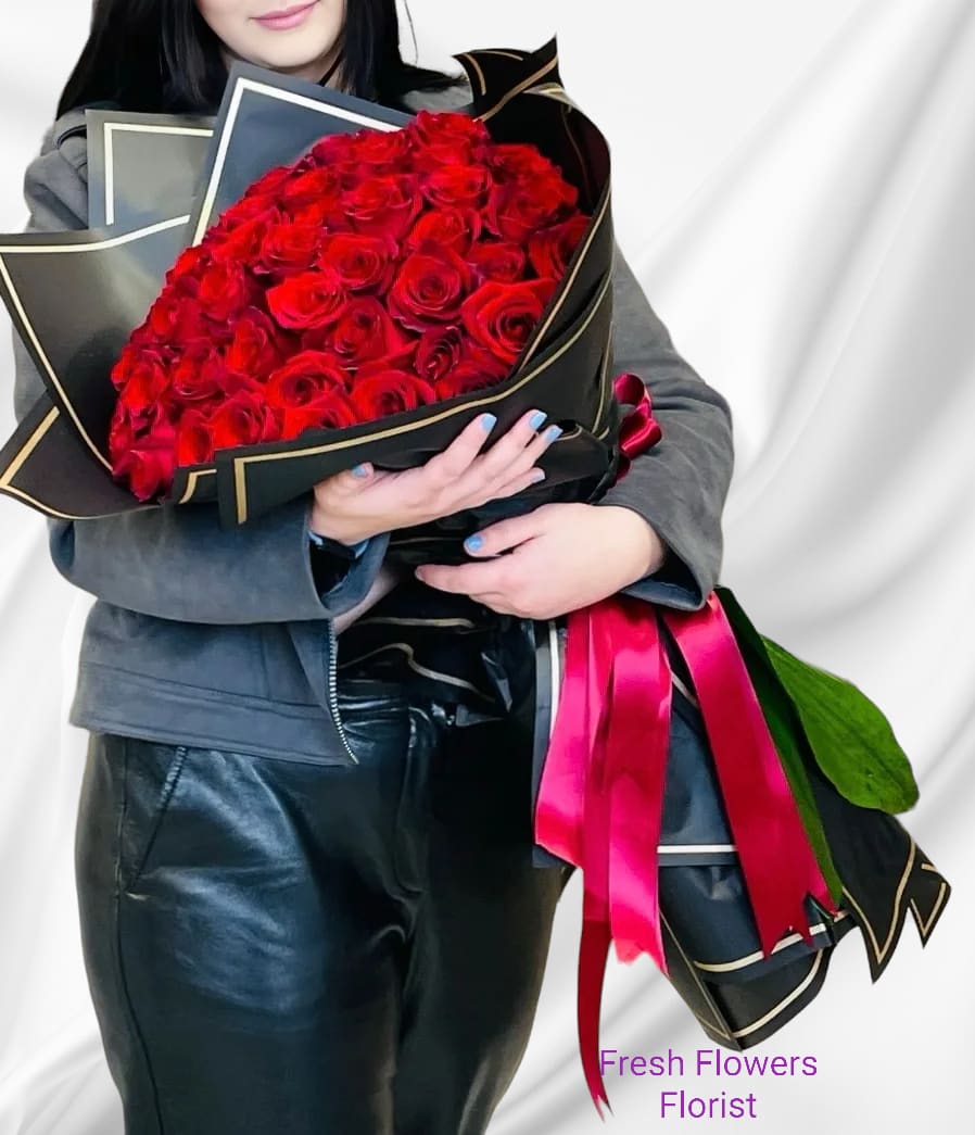 Large bouquet of red roses wrapped in black paper with pink ribbon