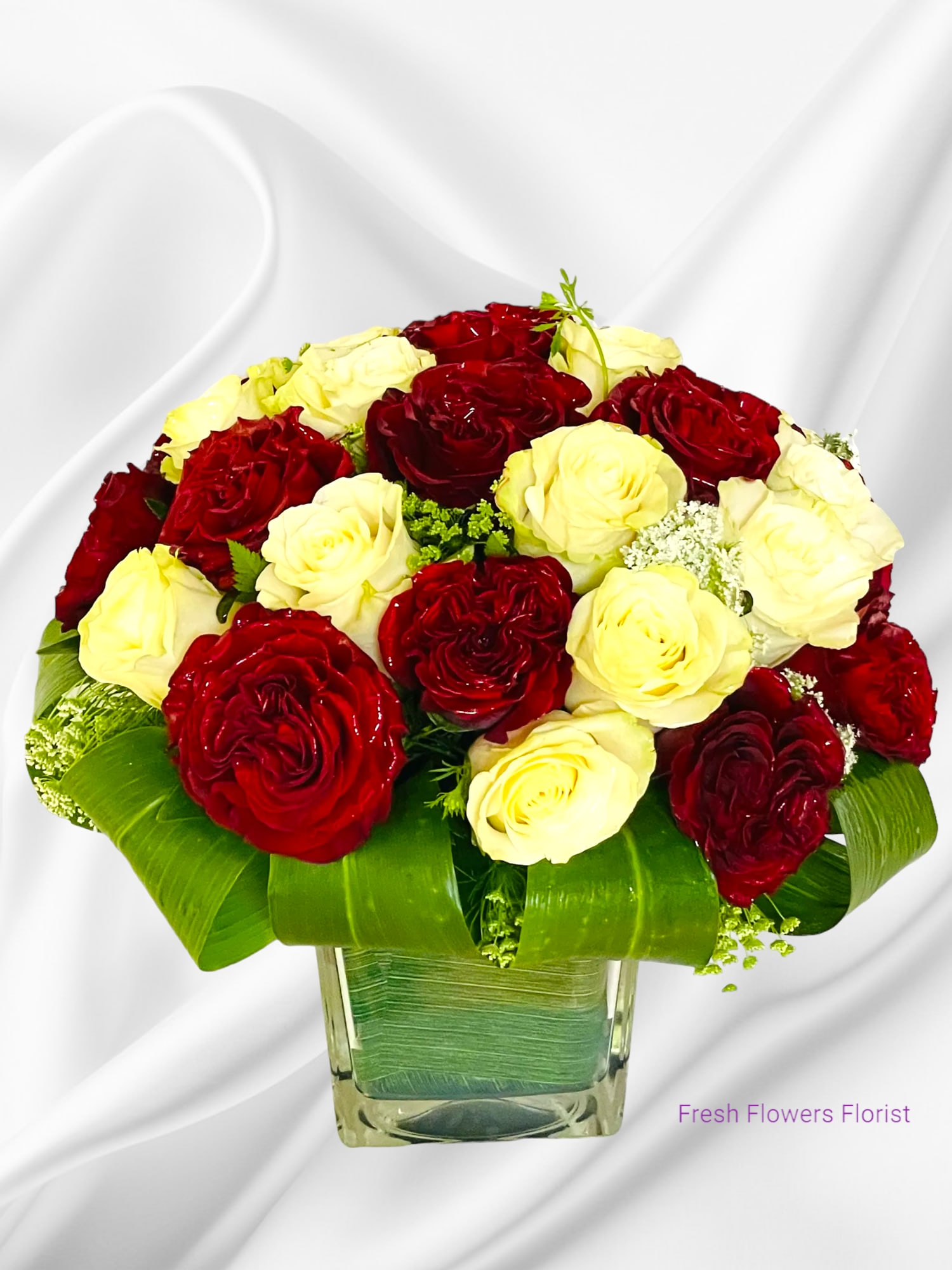 Red and pale yellow roses arranged in a clear square vase