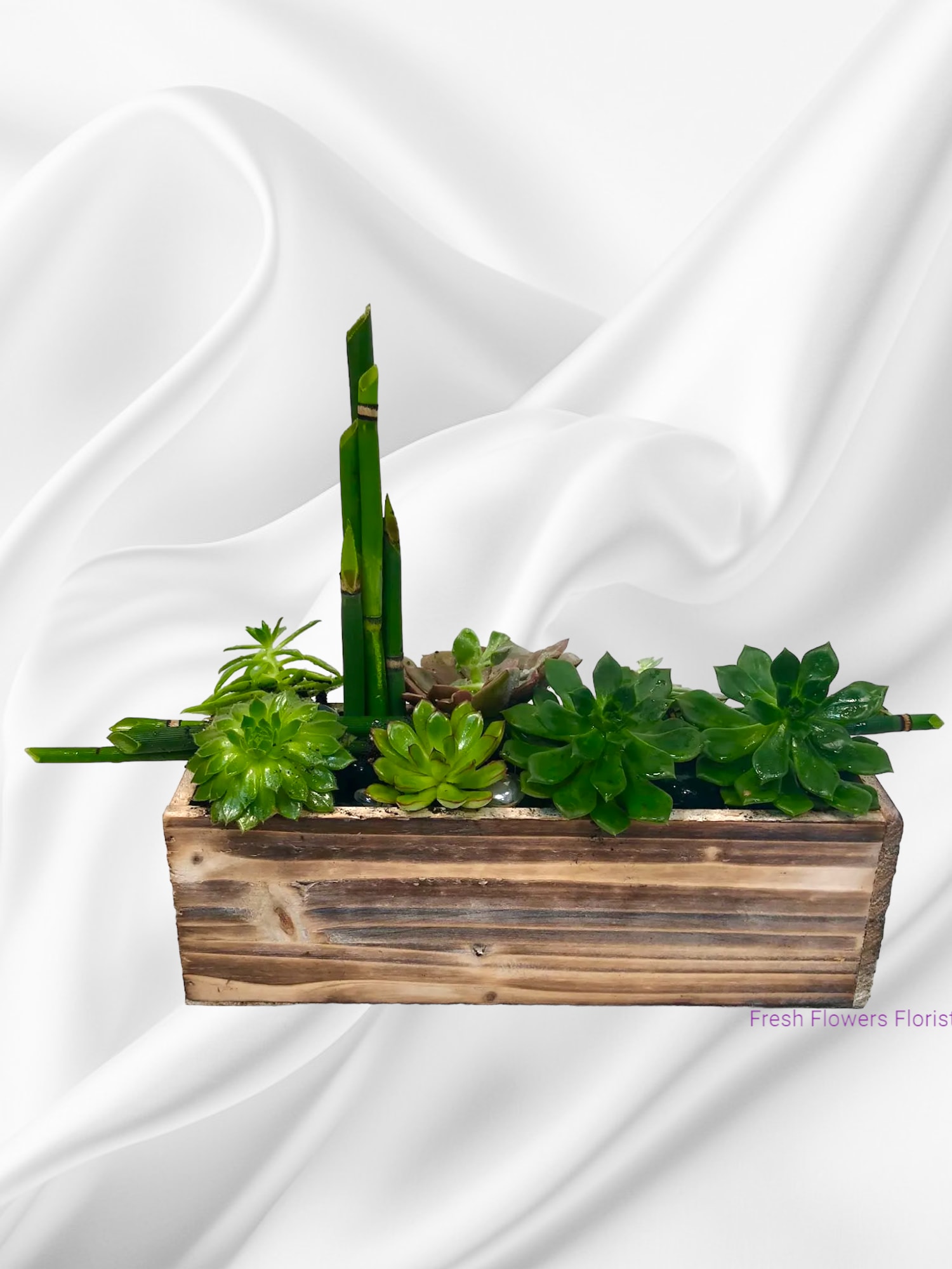 Succulent arrangement in a wooden planter with tall bamboo stalks